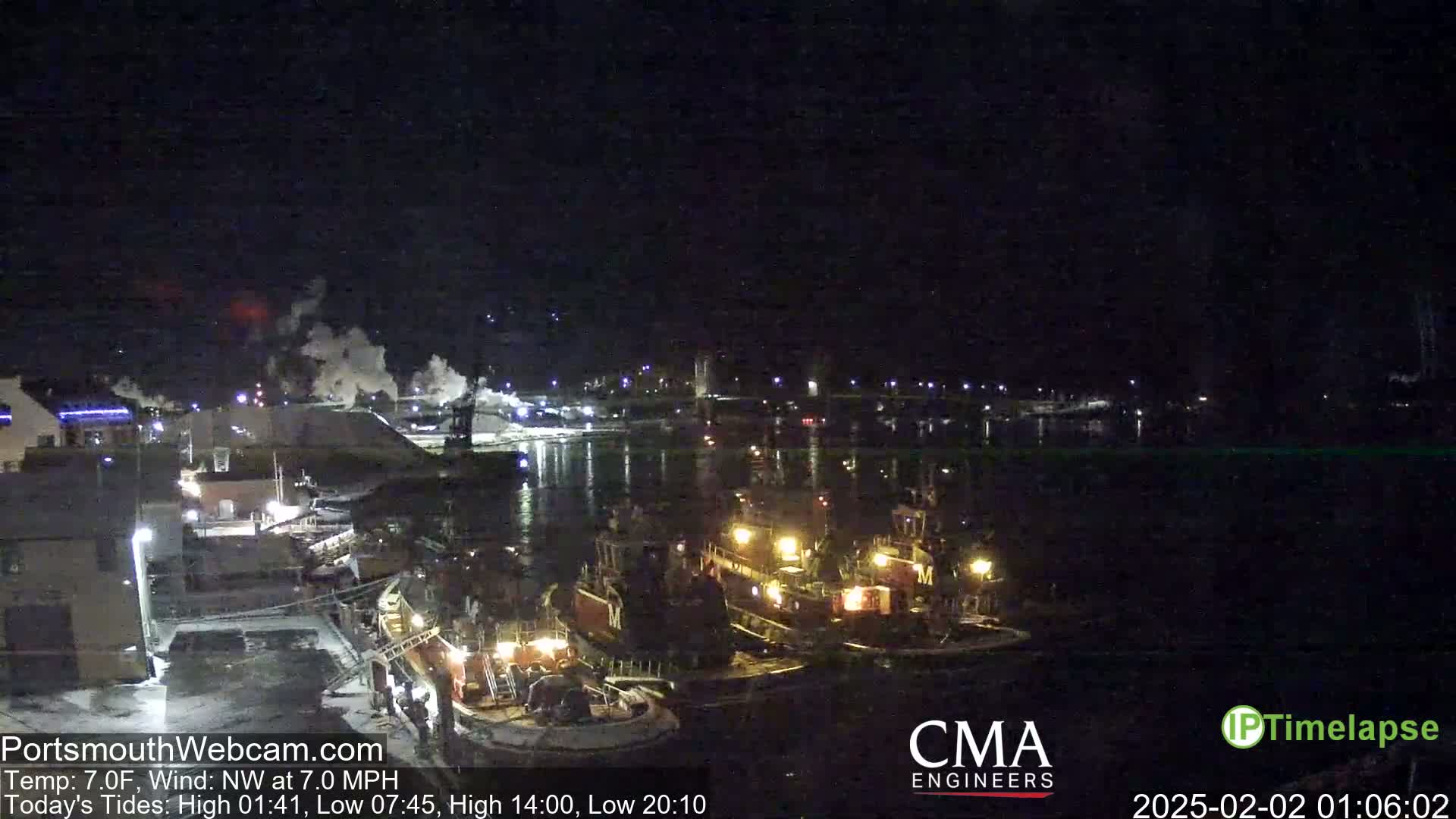 Several tugboats are docked at a nighttime harbor under a clear, dark sky.