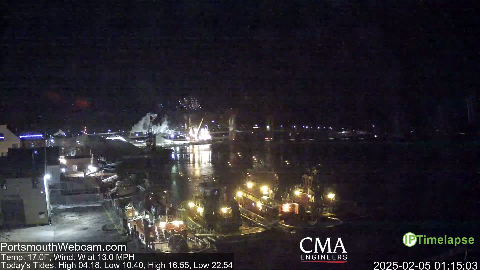 Several tugboats are docked at a nighttime harbor under a dark, clear sky.
