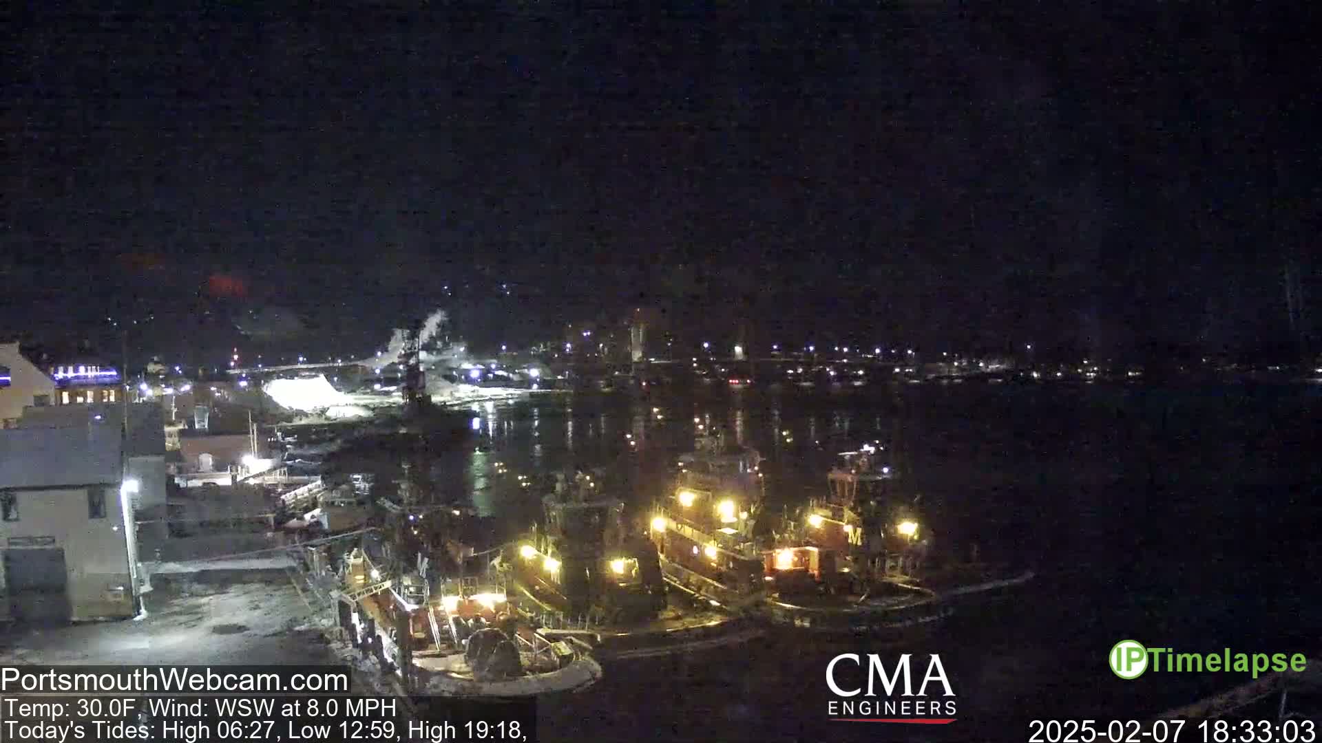 Several tugboats are moored at a dock at night in a harbor, under a dark sky with a temperature of 30°F and a wind from the west-southwest at 8.0 mph.