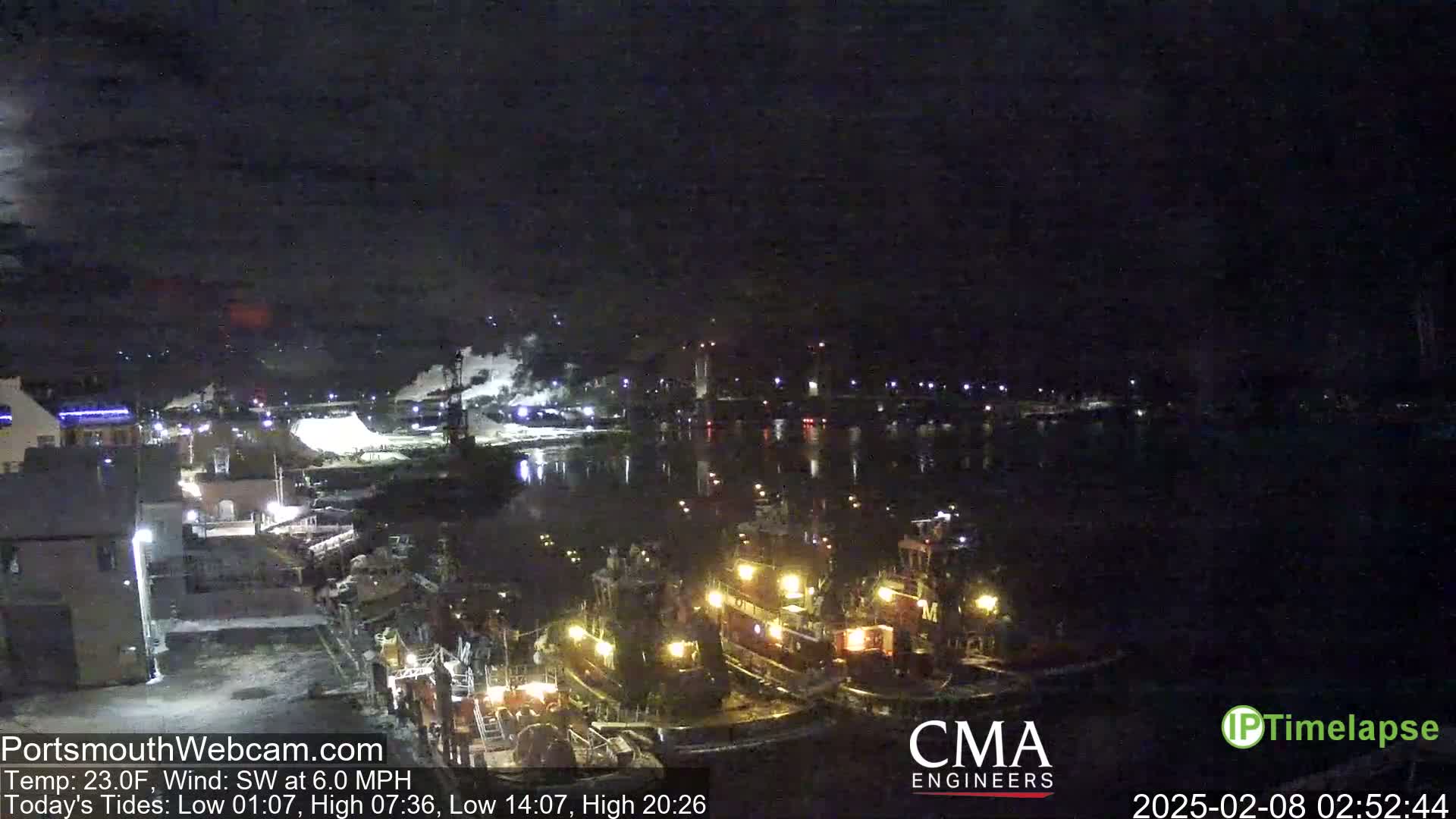 Several tugboats are docked at a nighttime harbor under a dark, clear sky.