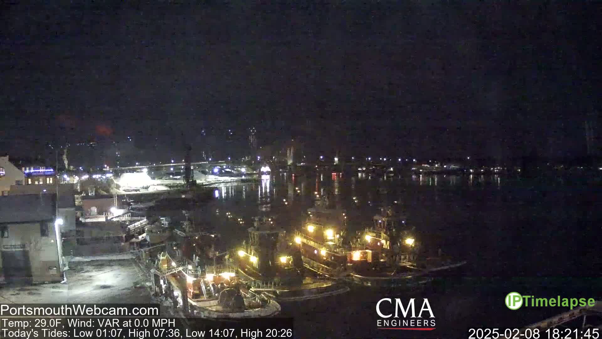 Several tugboats are moored at a dock at night under a clear, dark sky.