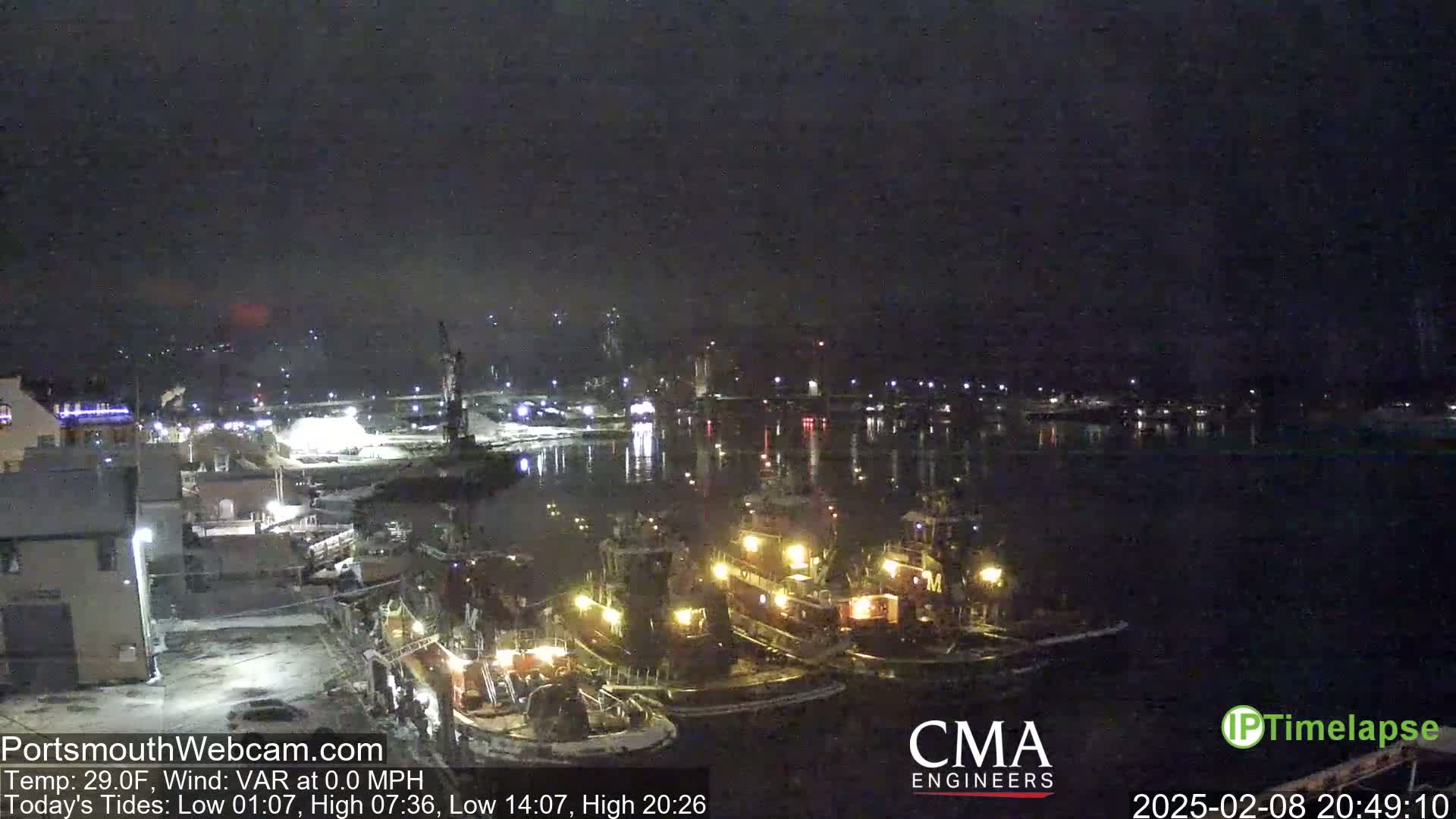 Several tugboats are moored in a harbor at night under a clear, dark sky.