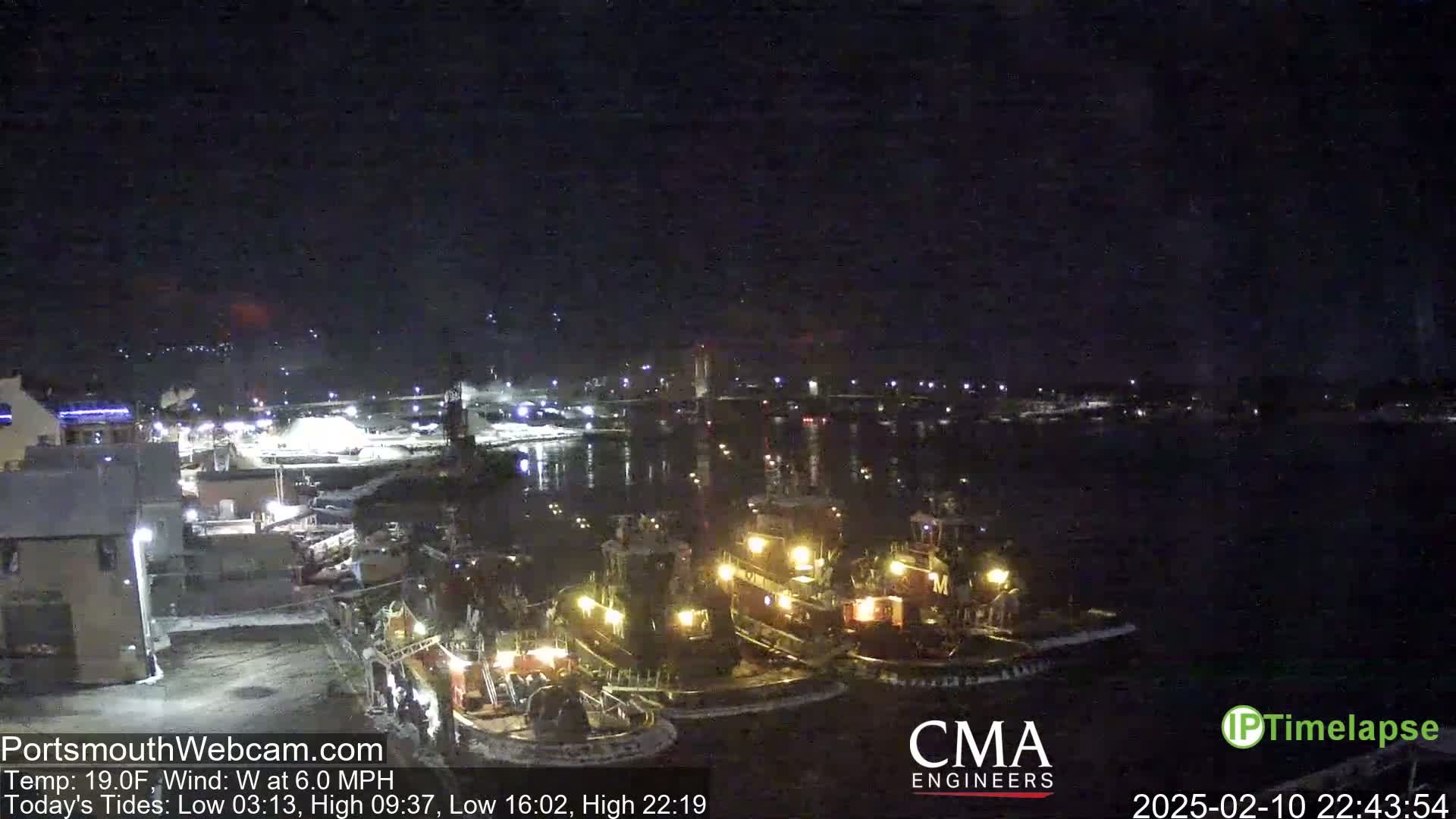 Several tugboats are moored in a dark harbor at night under a clear sky.