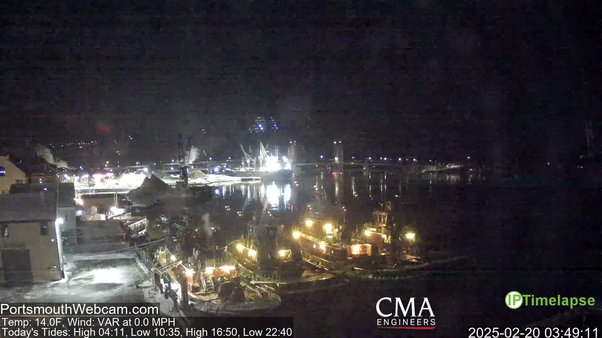 Several tugboats are docked at a harbor at night in 14°F weather with a variable wind at 0.0 mph.