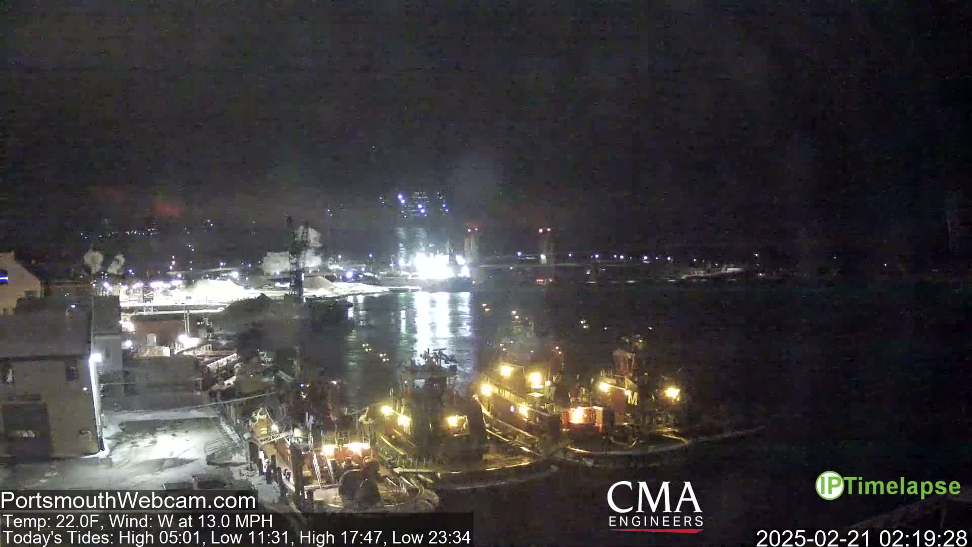 Several tugboats are moored at a dock at night in a harbor, under a dark sky with a  wind of 13 mph.