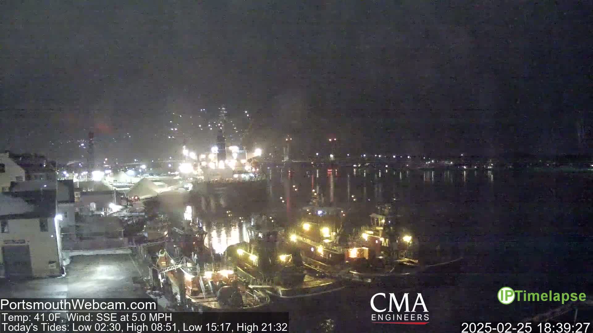 Several tugboats are docked at a nighttime harbor under a dark, clear sky.