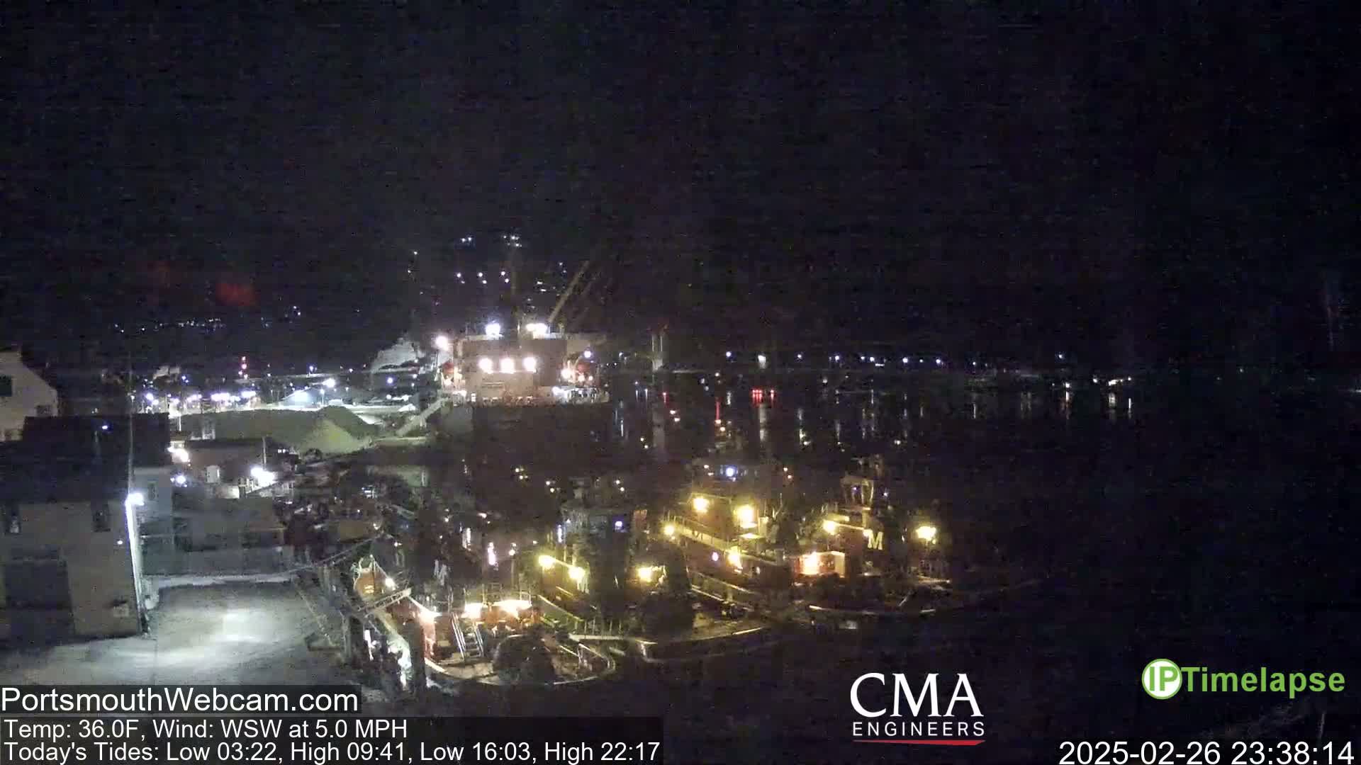 Several tugboats are moored at a dock at night under a dark, clear sky.