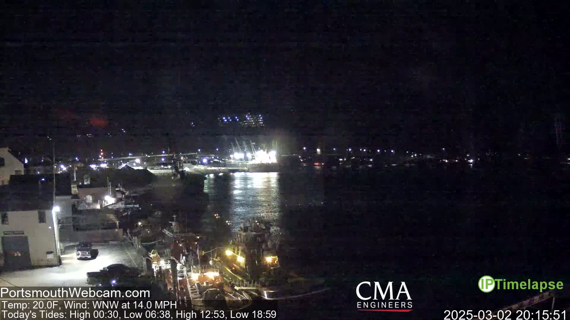 A nighttime harbor scene shows several boats illuminated near a dock, under a dark sky with a temperature of 20 degrees Fahrenheit and a west-northwest wind.