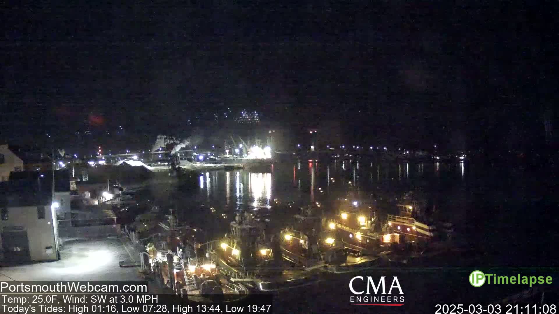 A nighttime view of a harbor with several docked boats and ships, under a clear, dark sky.