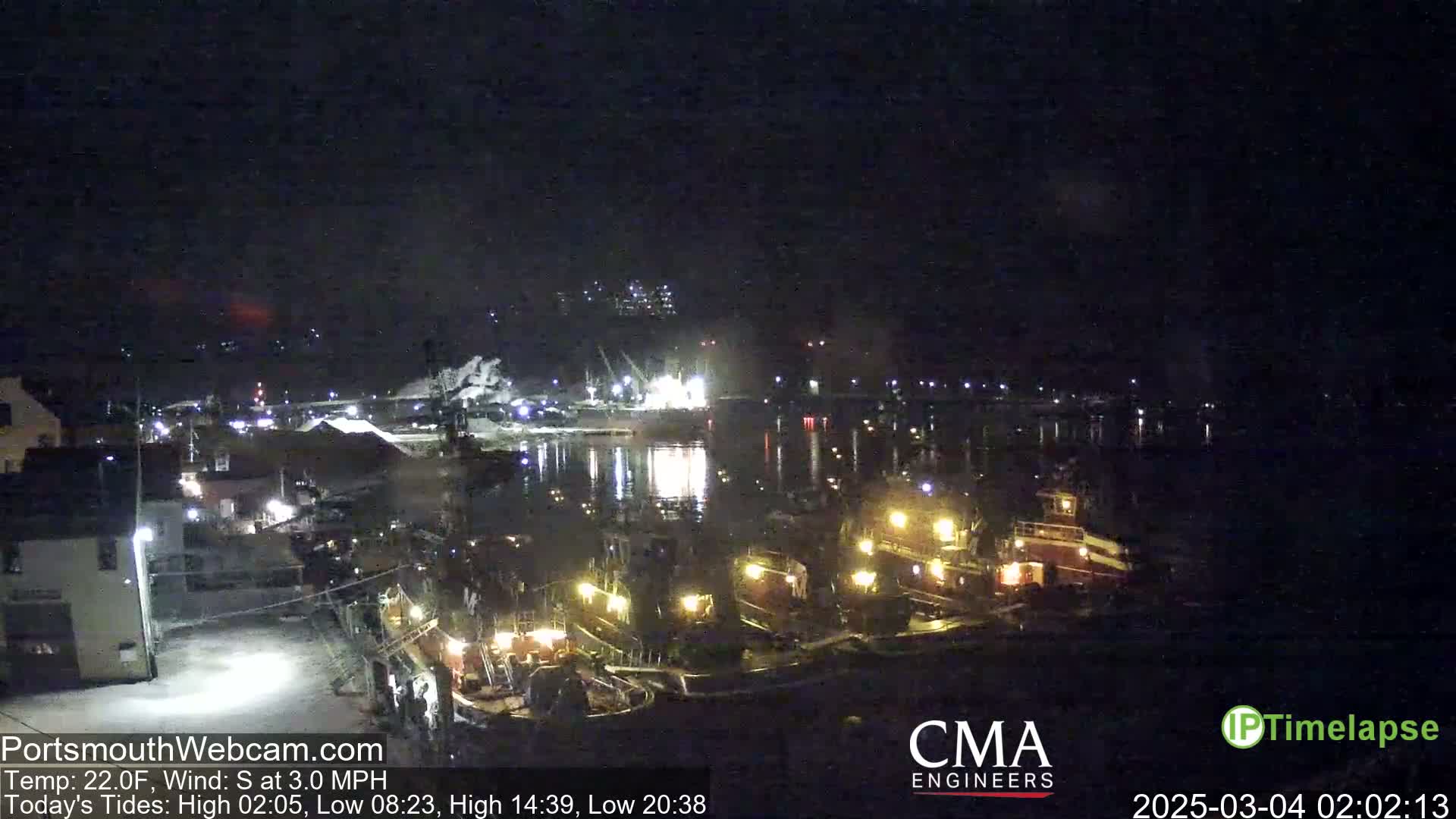 Several tugboats are docked at a harbor at night under a clear, dark sky.