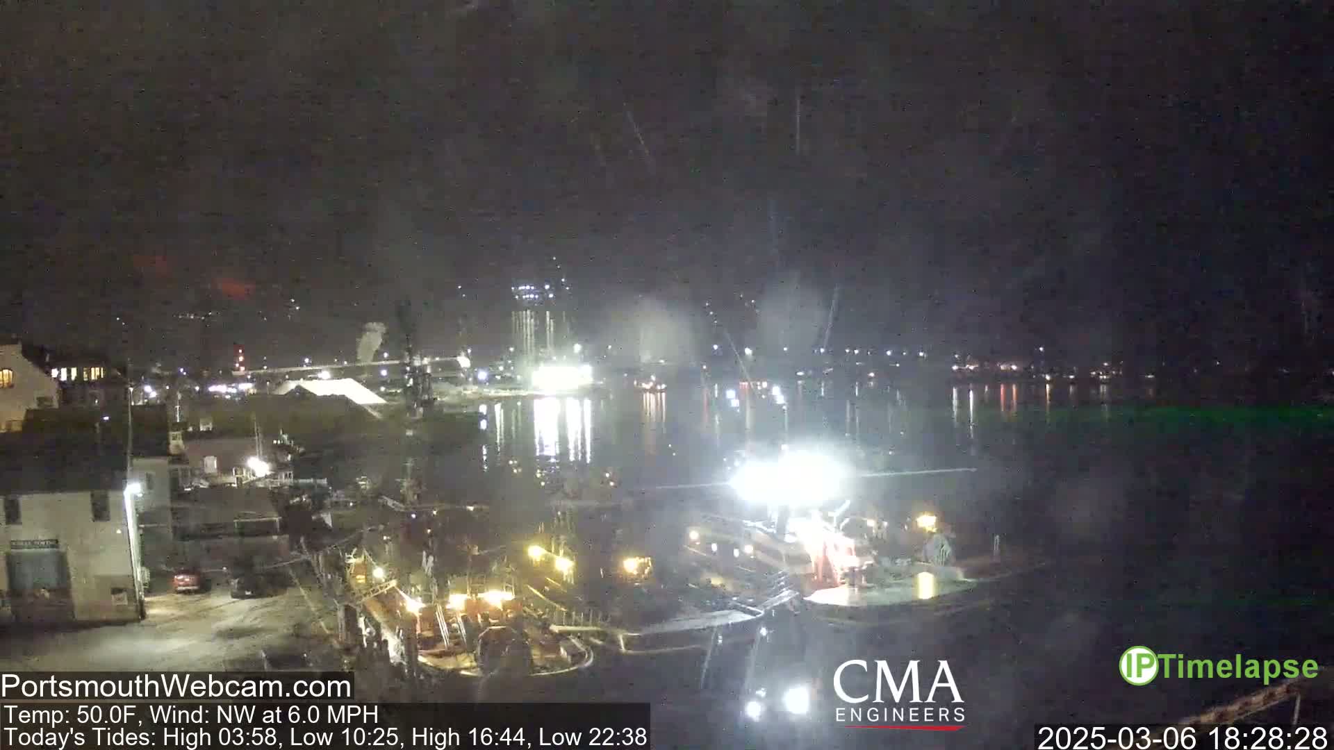A nighttime harbor scene with several boats docked, under a slightly overcast sky with a northwest wind.
