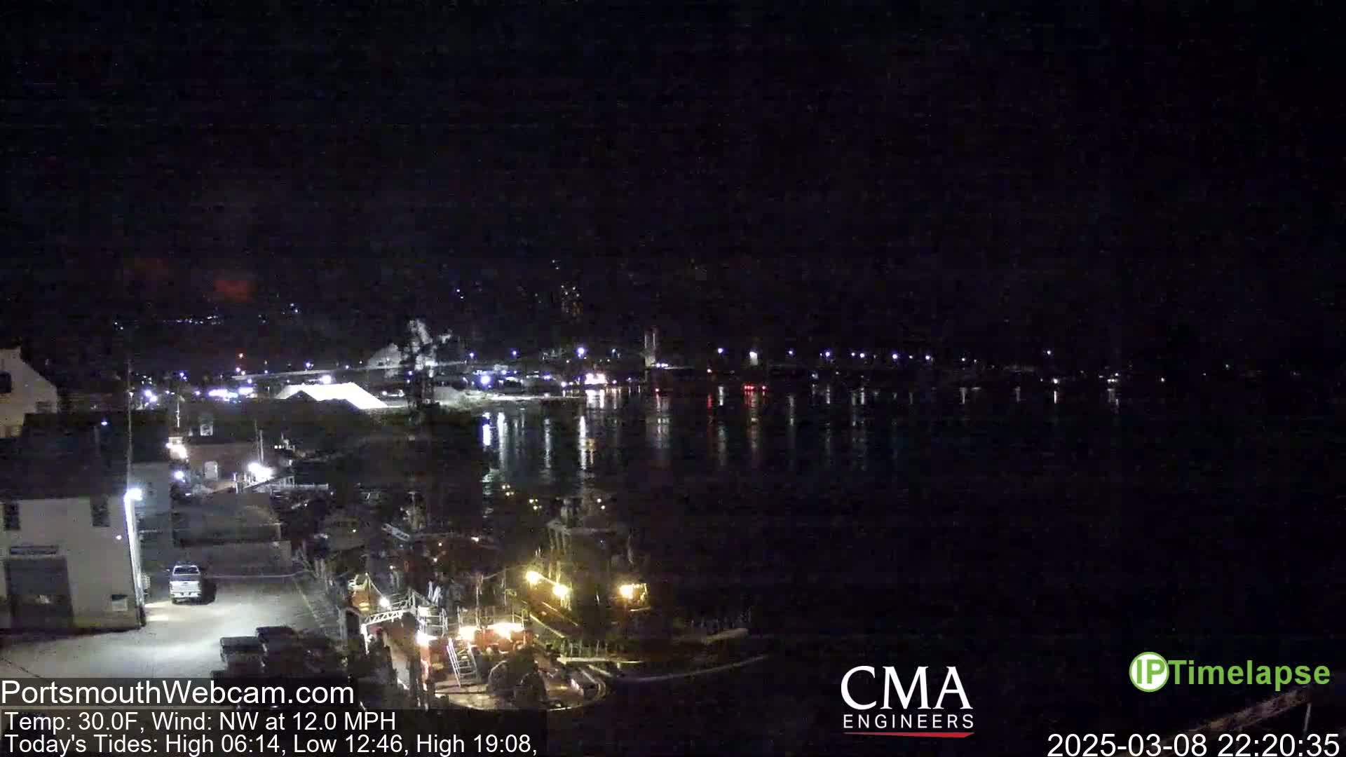 A nighttime view of a harbor with several boats docked, under a dark sky with a northwest wind.