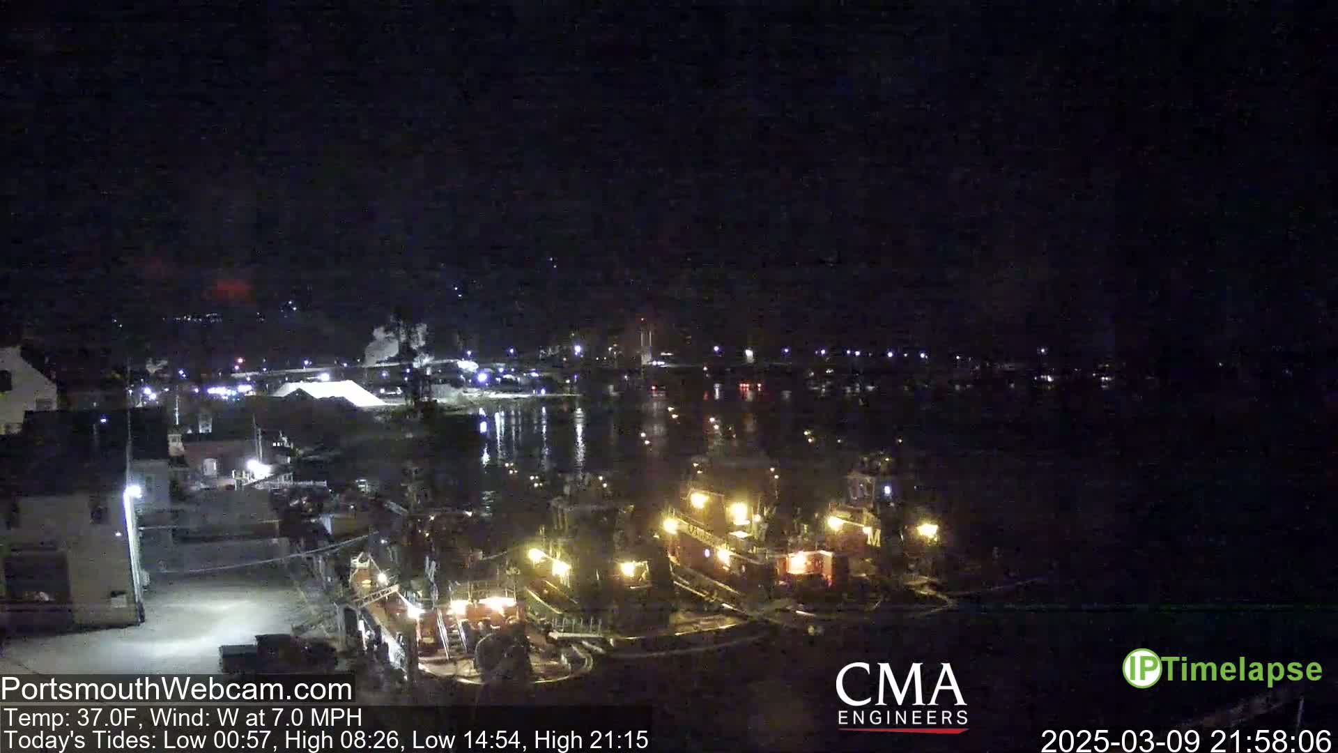 Several tugboats are docked at a harbor at night under a clear, dark sky.