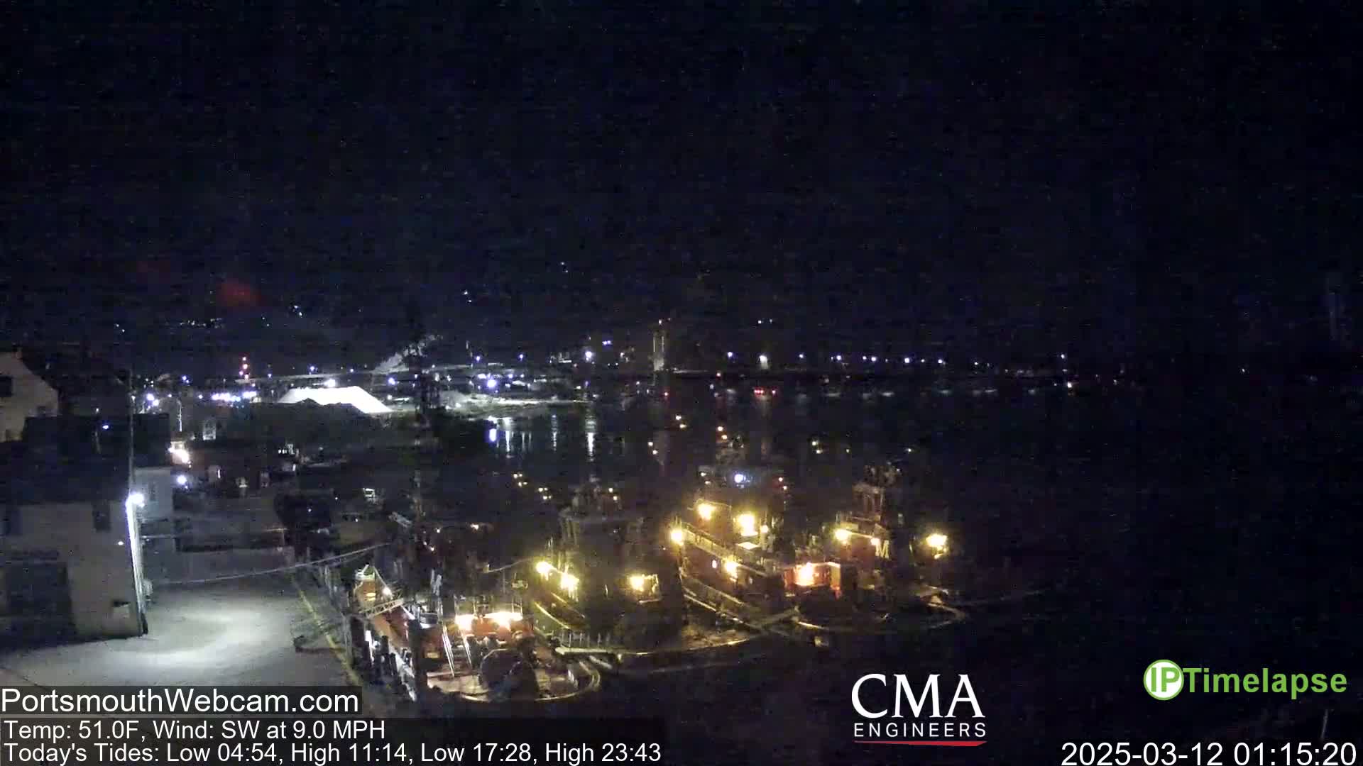 Several tugboats are docked at a waterfront at night under a dark, clear sky with a southwest wind.
