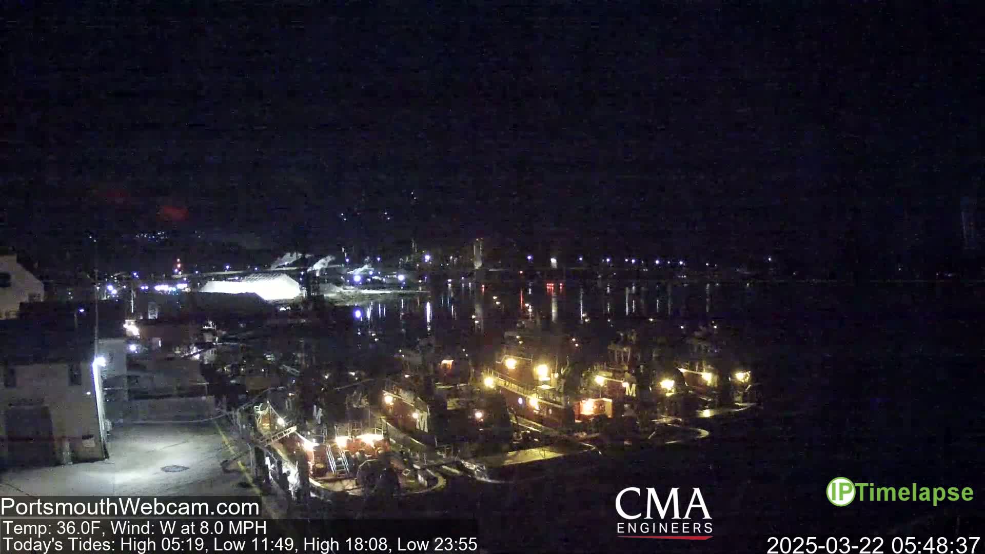 Several tugboats are docked at a harbor at night under a clear, dark sky.