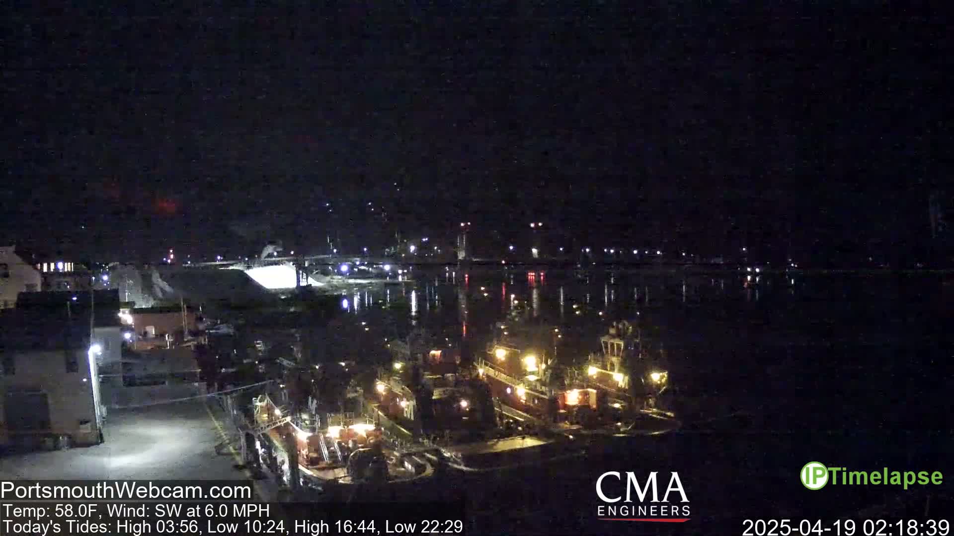 Several tugboats are docked at a harbor at night, under a clear, dark sky with a southwest wind.