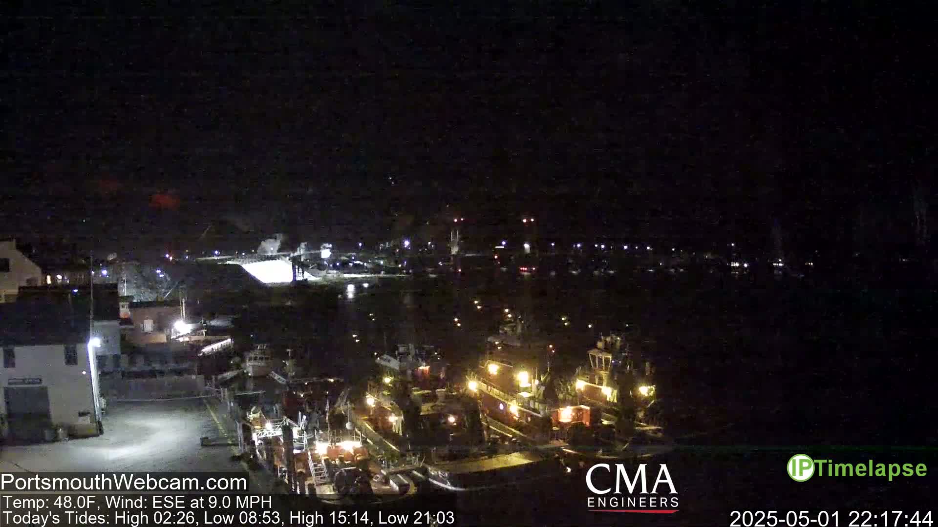 Several boats are docked at a harbor at night under a dark sky.