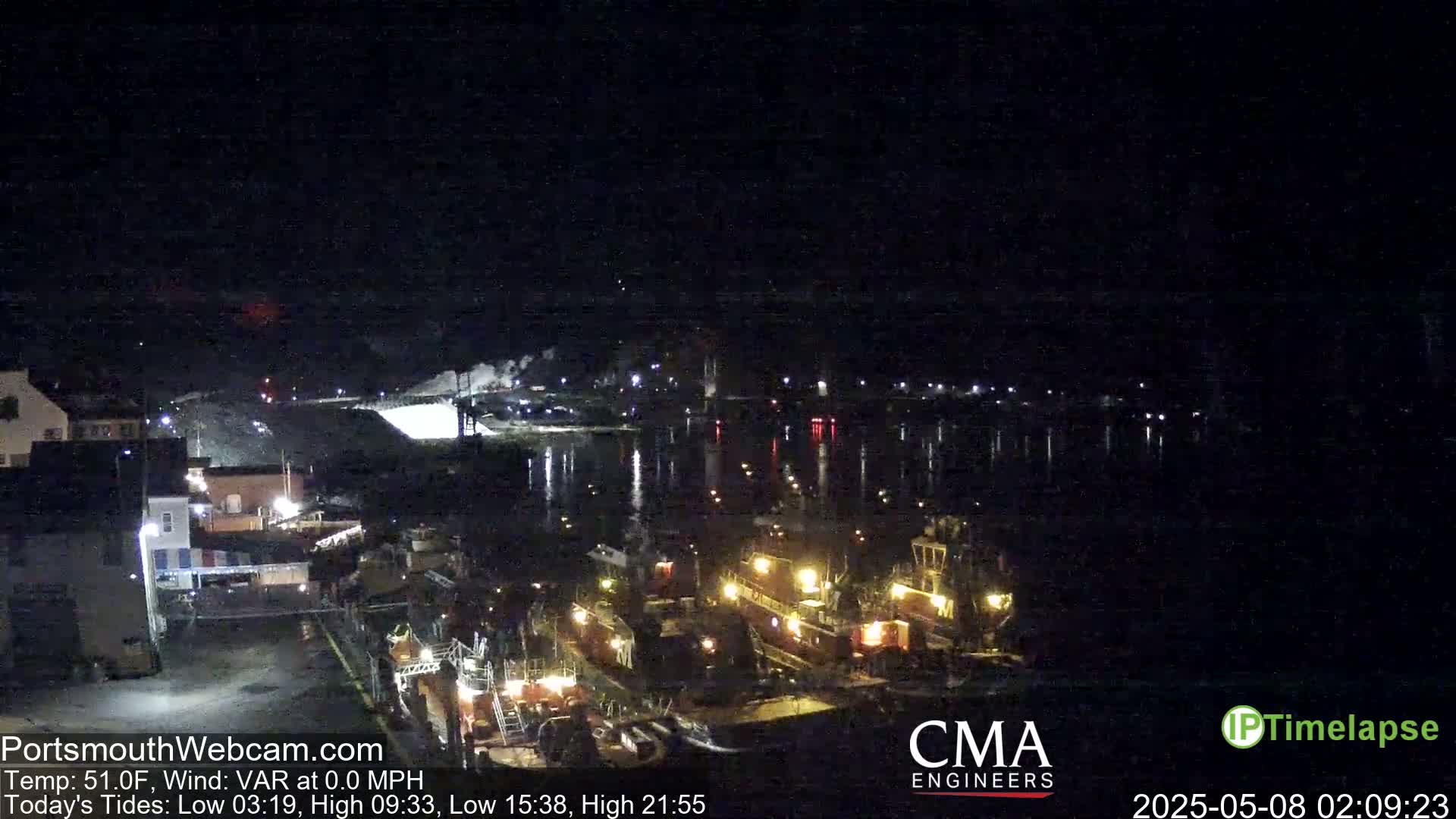 Several boats are docked at a nighttime harbor under a clear, dark sky.
