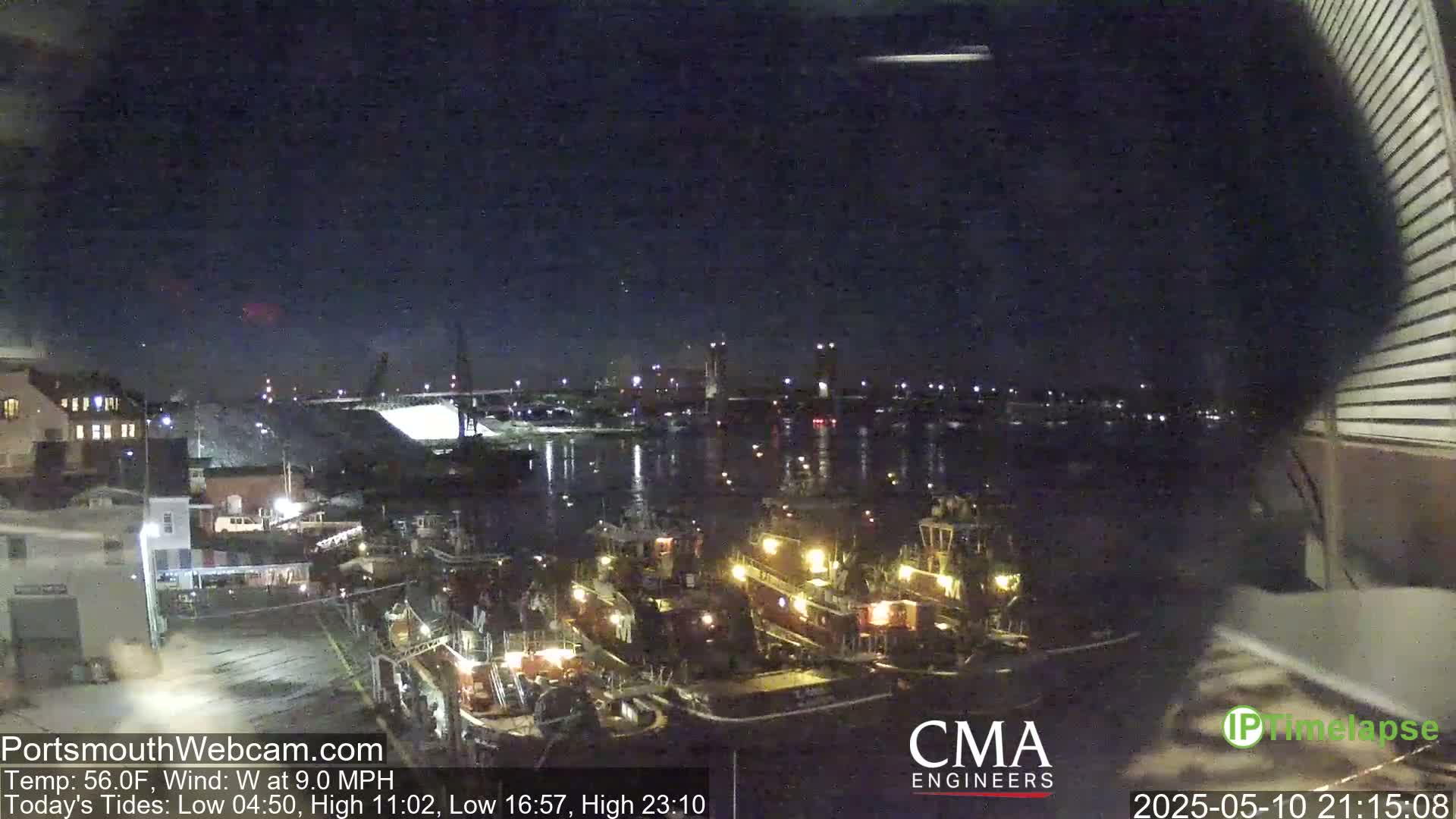 Several tugboats are docked at a waterfront at night under a clear, dark sky with a gentle west wind.