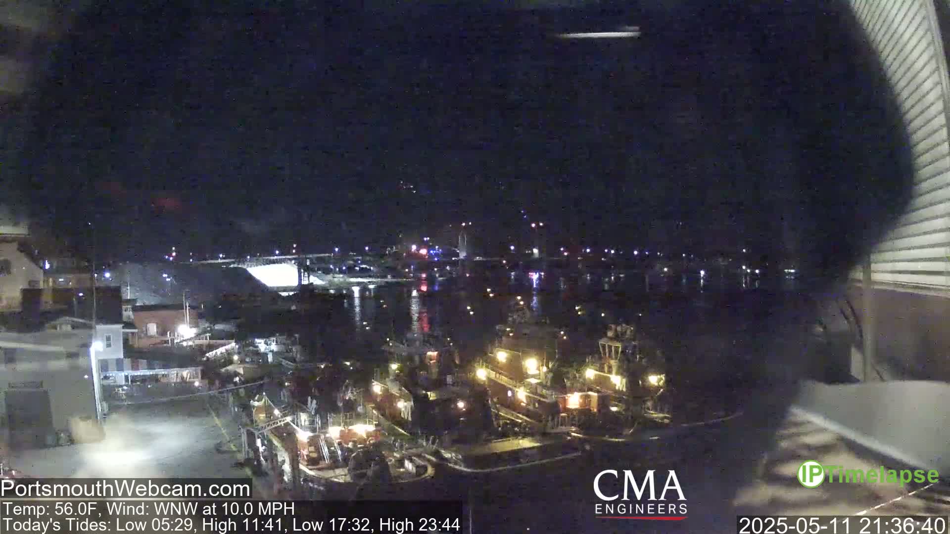 Several tugboats are docked at a harbor at night under a dark, clear sky with a 10 mph wind.
