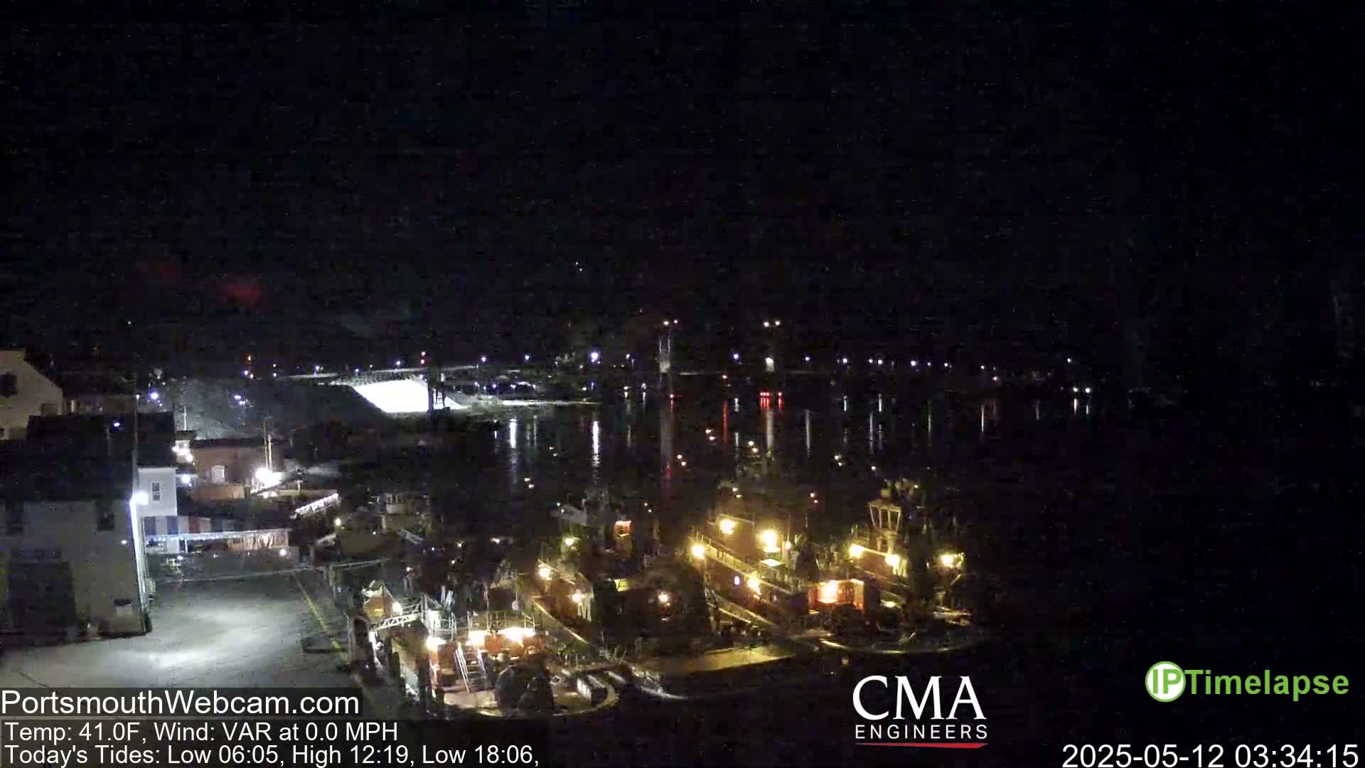 Several tugboats are docked at a harbor at night under a clear, dark sky.