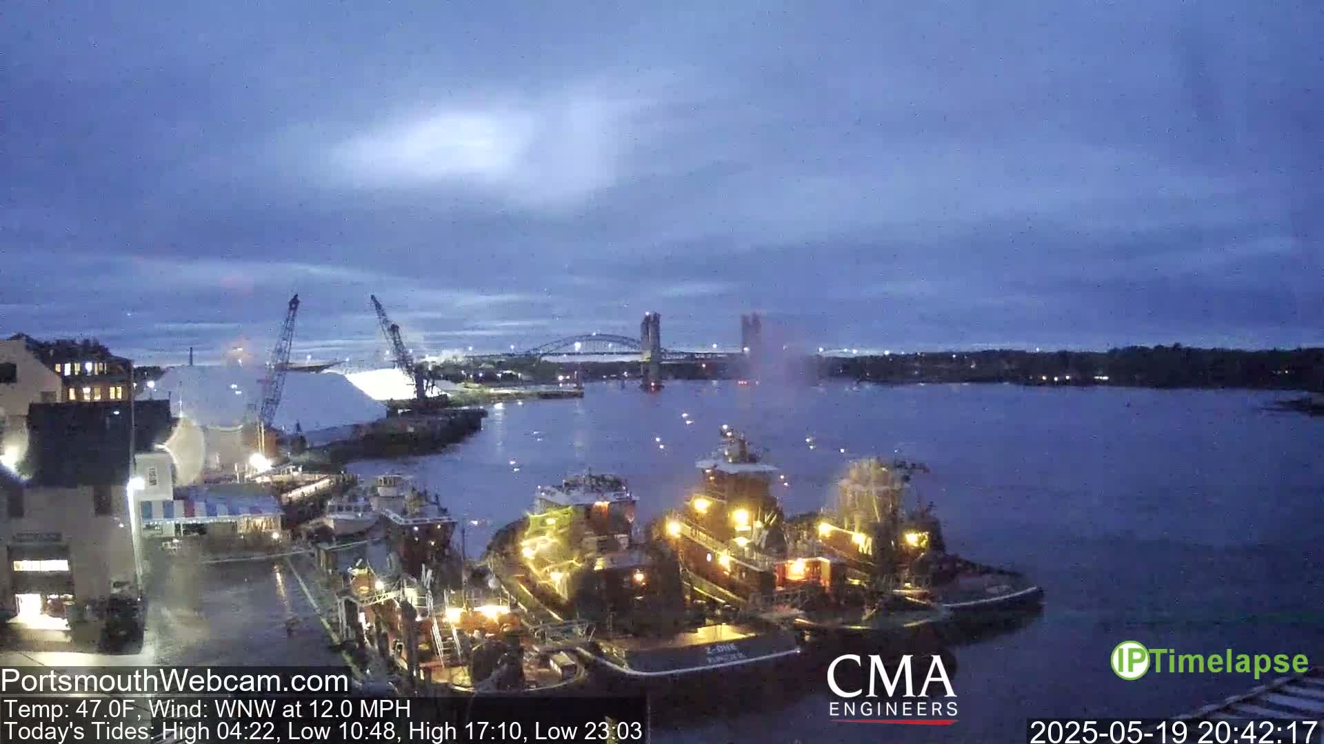 Several tugboats are docked at a harbor under a twilight sky with a WNW wind at 12.0 mph.
