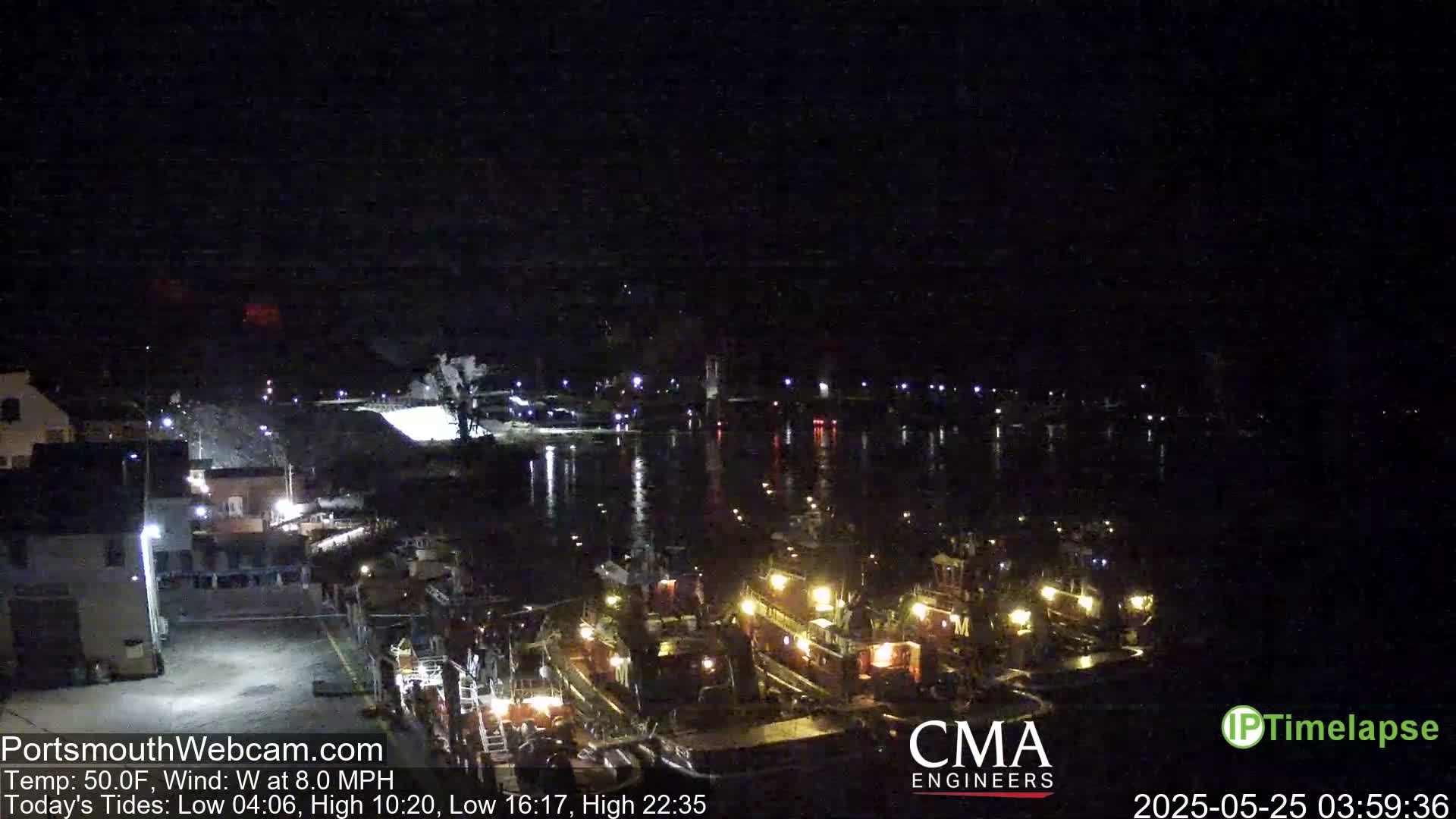 Several tugboats are docked at a harbor at night, under a clear sky with a west wind.