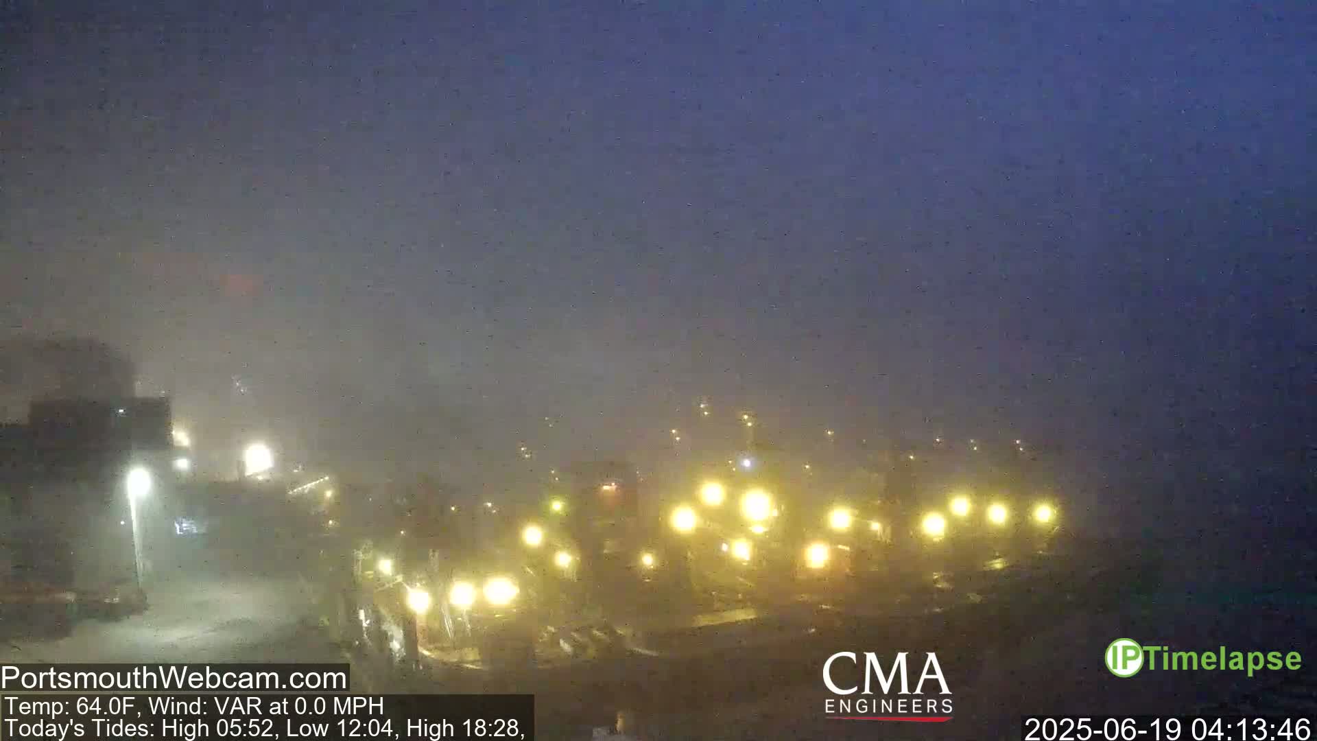 A foggy night scene shows a line of vehicles with headlights illuminated.