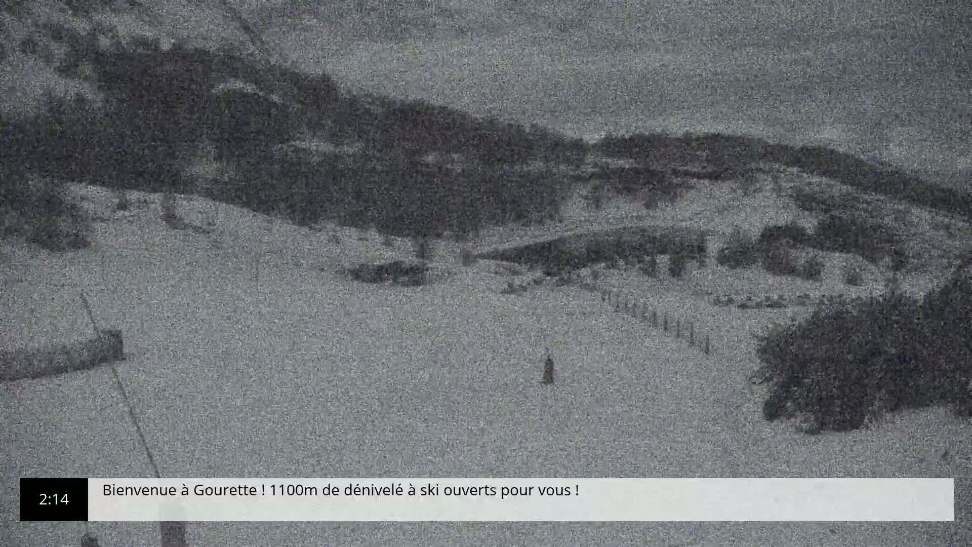 A snow-covered ski slope is visible, with some skiers or snowboarders present, under what appears to be overcast conditions.