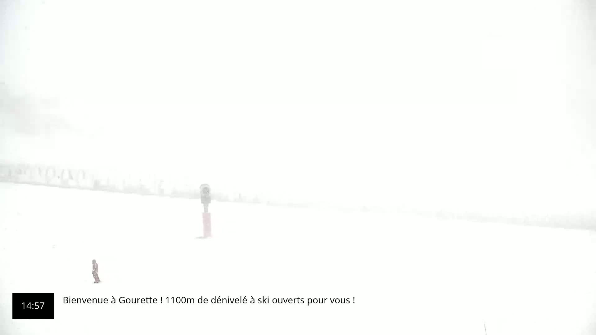 A lone figure stands on a snow-covered expanse in heavy whiteout conditions.