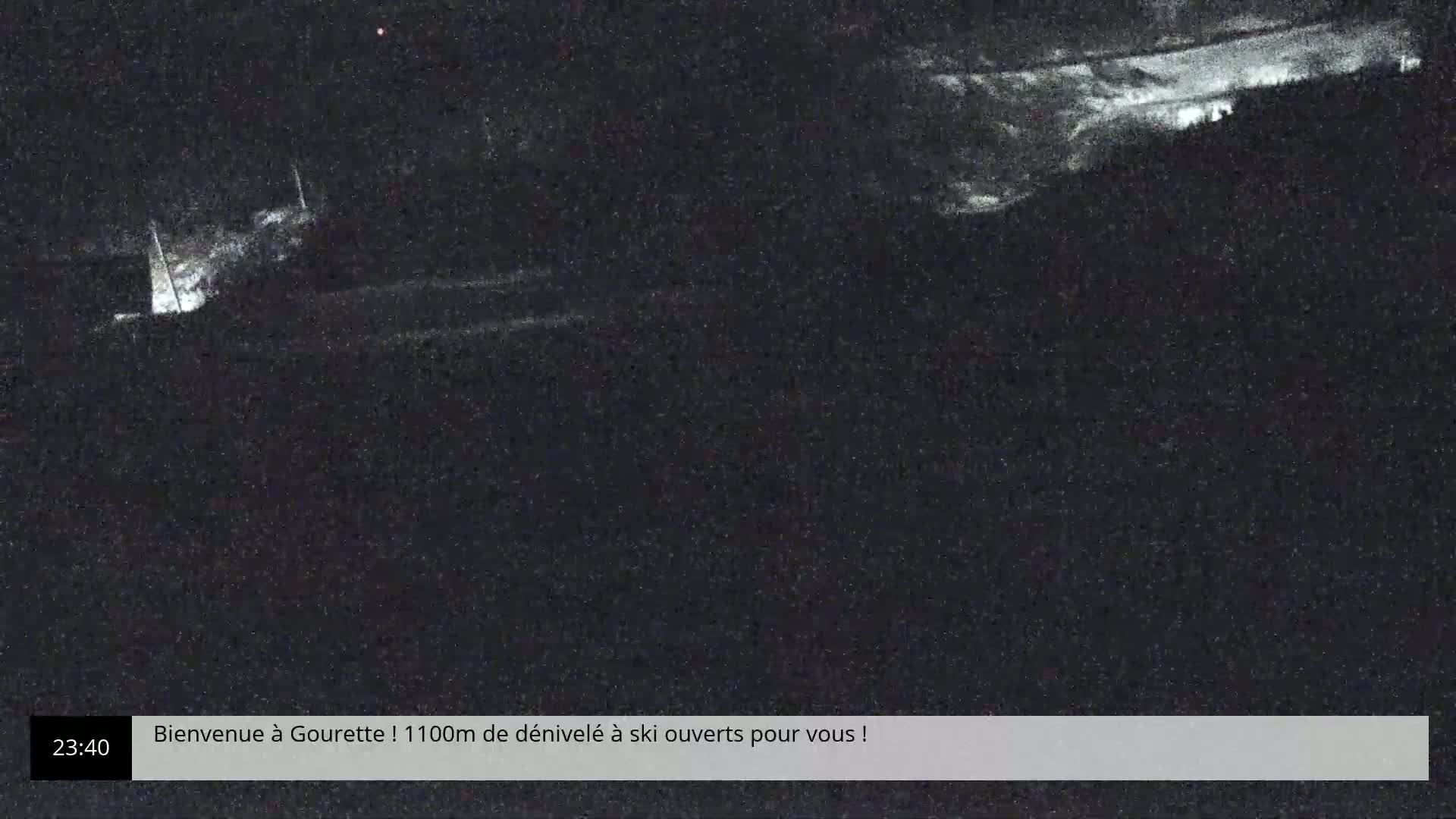A nighttime, low-light view shows a dark landscape with some indistinct bright areas.