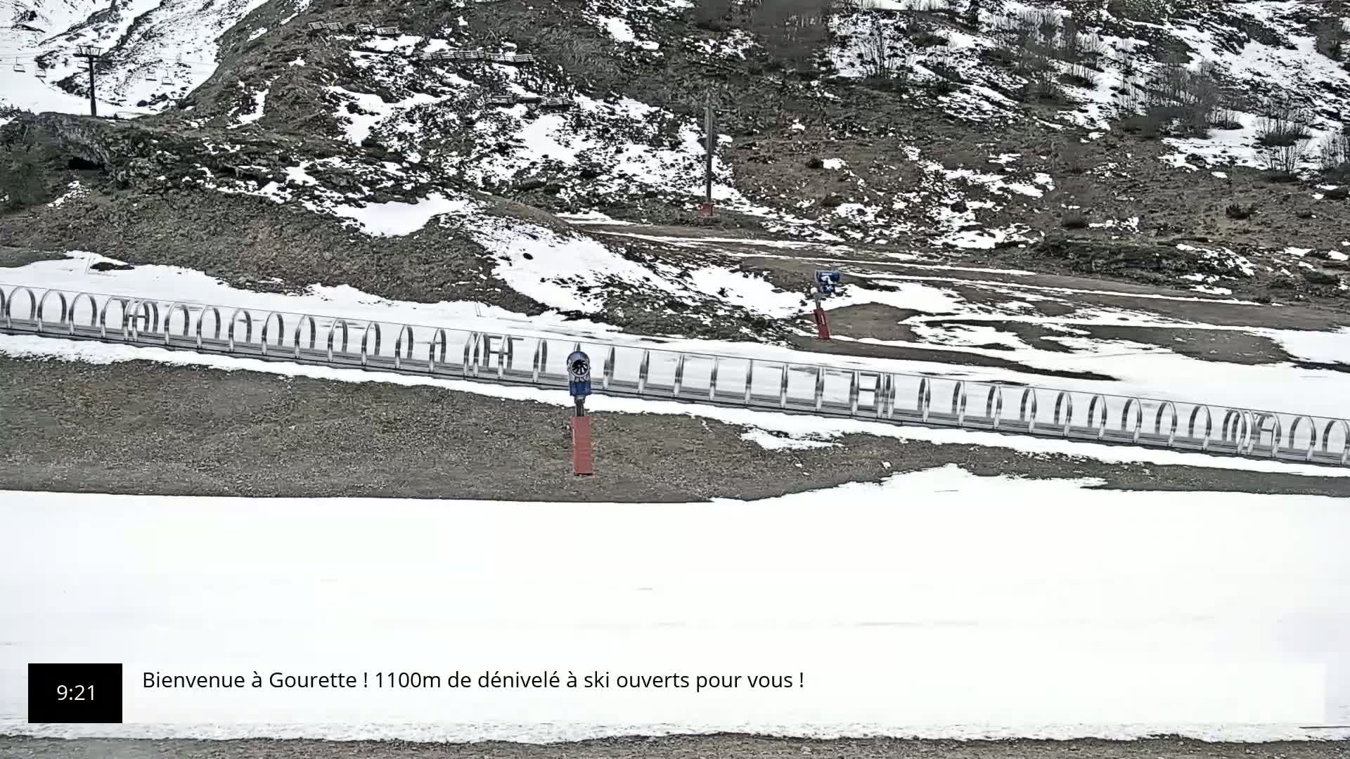 A snowy, rocky hillside with snowmaking equipment and a partially snow-covered ground.