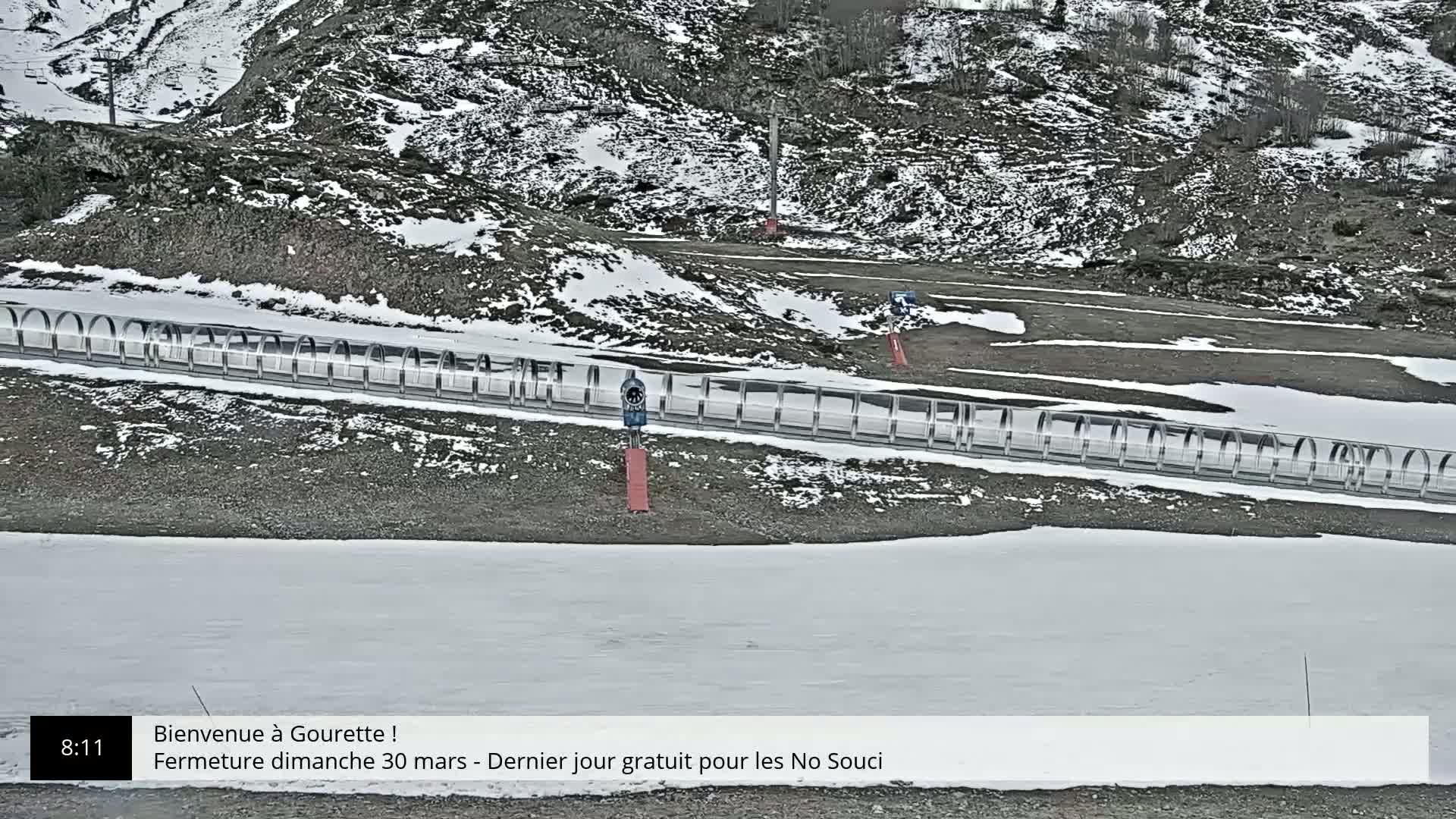 A snow-covered ground with a long, transparent tubular structure and a rocky, snow-dusted hillside in the background.