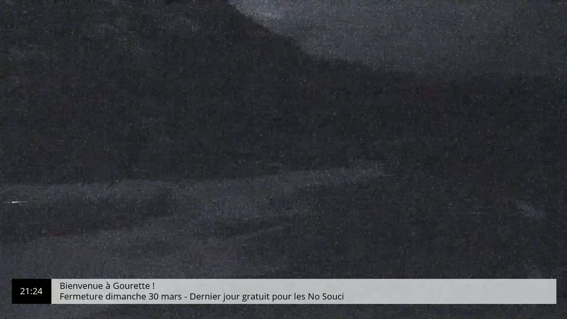 A dark, nighttime outdoor scene shows a blurry landscape under a cloudy sky.