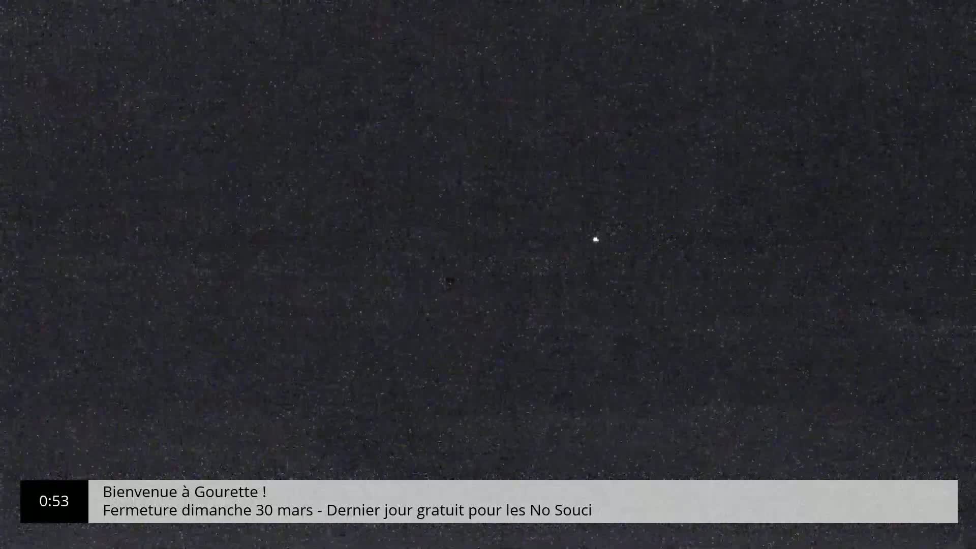 A dark, possibly nighttime, scene shows a speckled, dark gray surface with a few brighter specks scattered across it.
