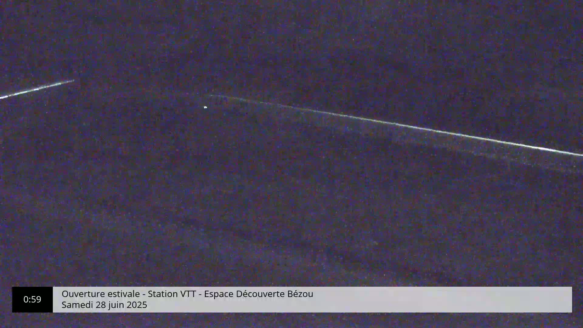 A dark, nighttime scene shows two faint, bright streaks across a dark sky.