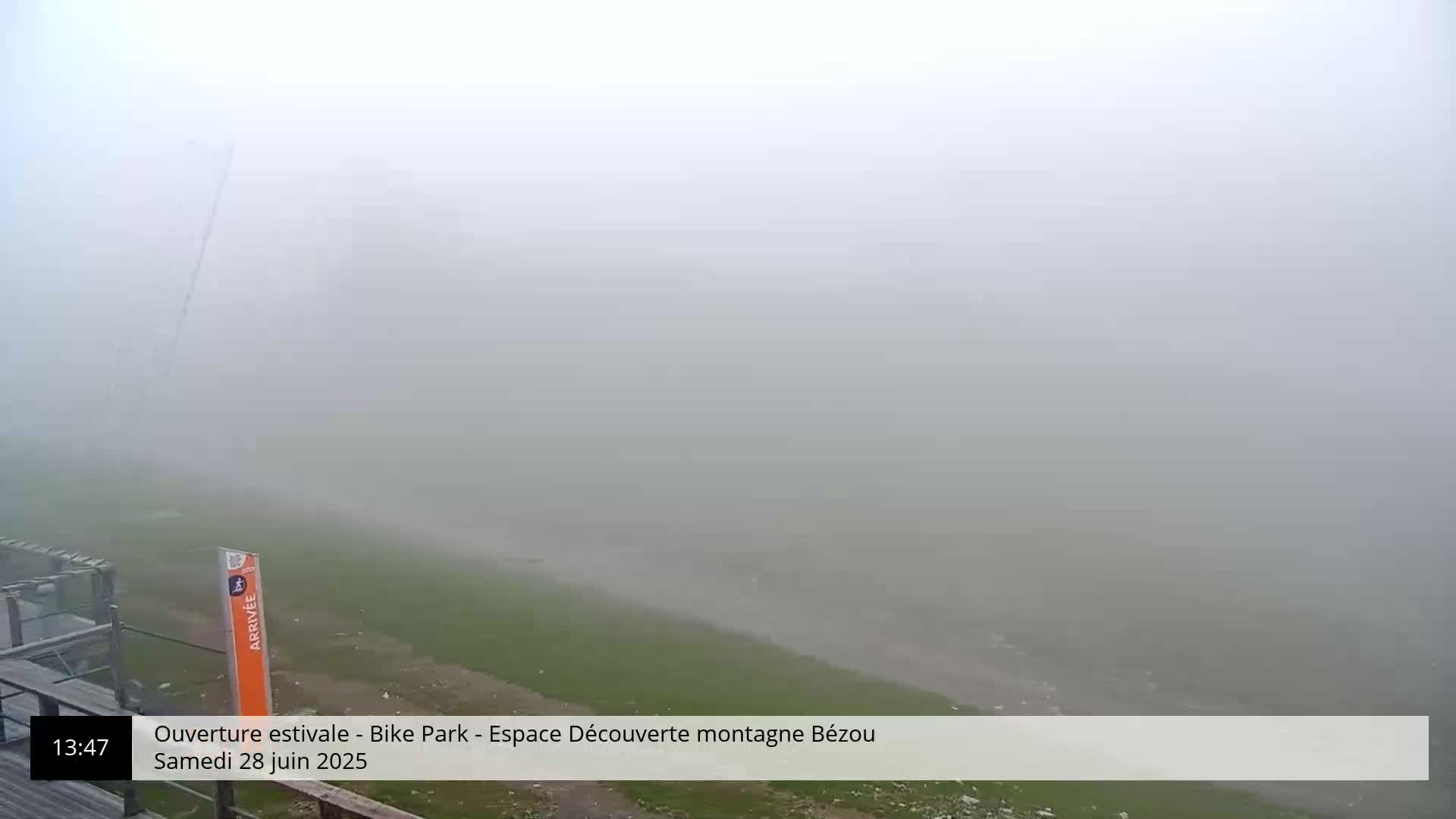 A foggy, grassy field is visible, with a portion of a structure and signage in the lower left corner.
