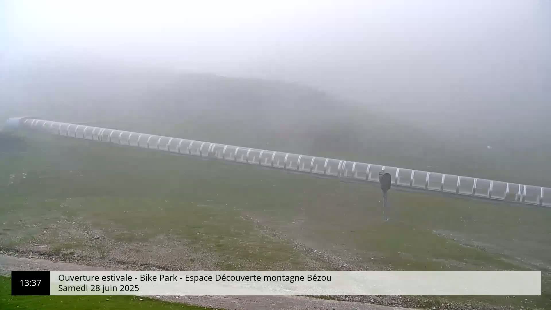 A long, covered structure extends across a foggy, grassy landscape.