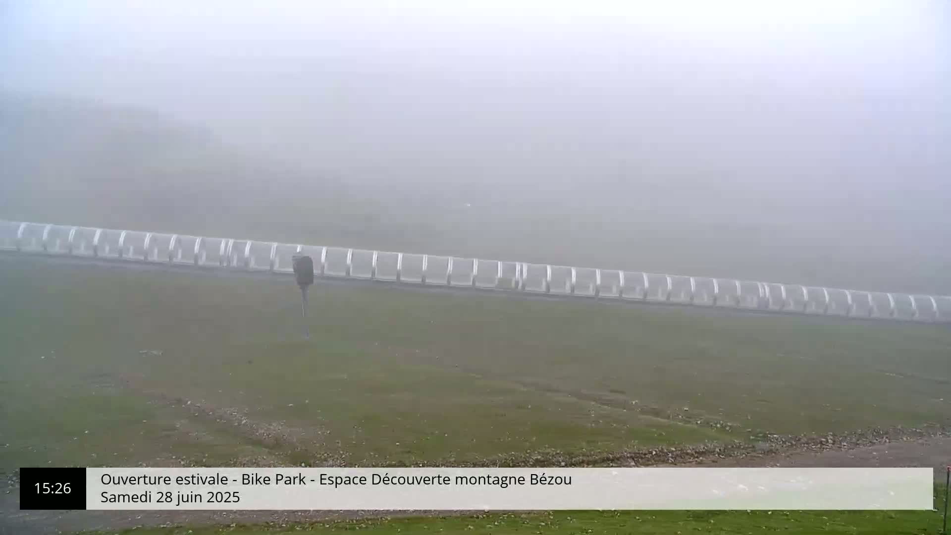A foggy field with a long row of covered bicycle racks.