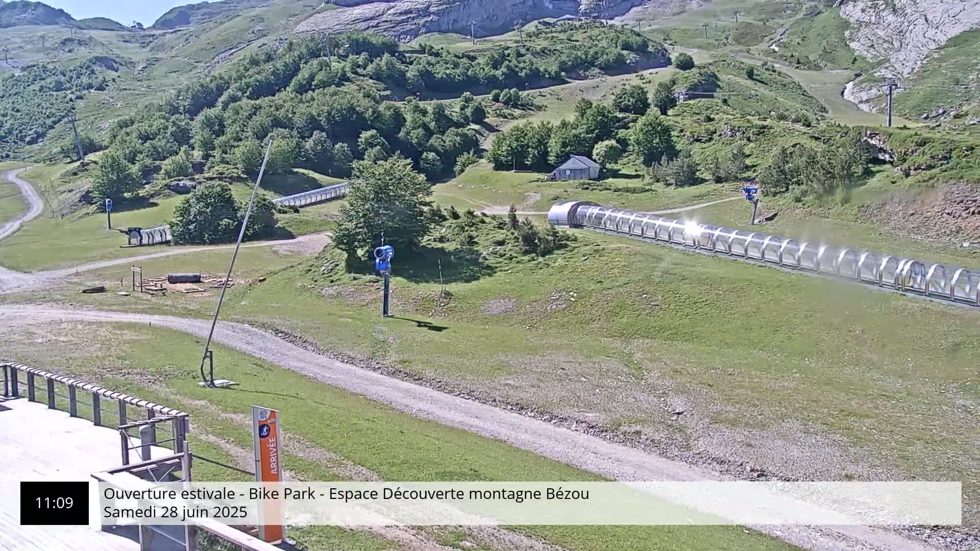A mountainside bike park with a covered track, under sunny conditions.