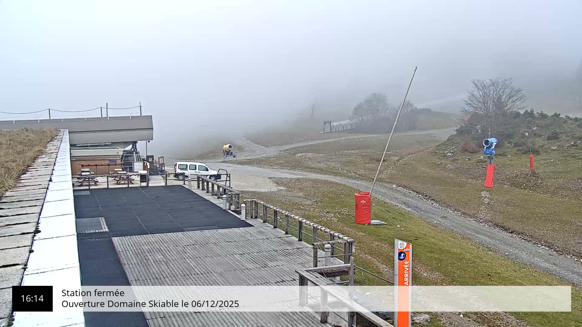 A foggy outdoor scene shows an empty outdoor cafe area with a red cable car, and a long cable stretching into the thick fog.