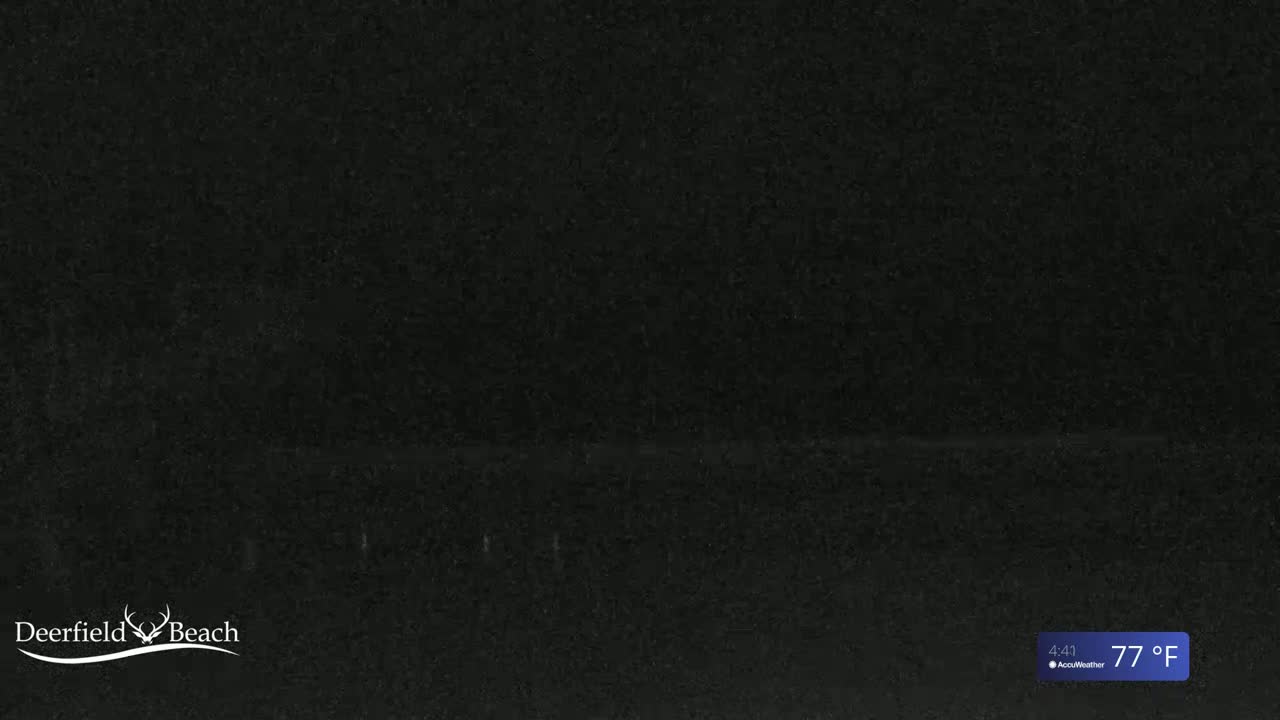 A mostly dark image shows a dark surface, possibly asphalt or pavement, under a night sky at 77°F.