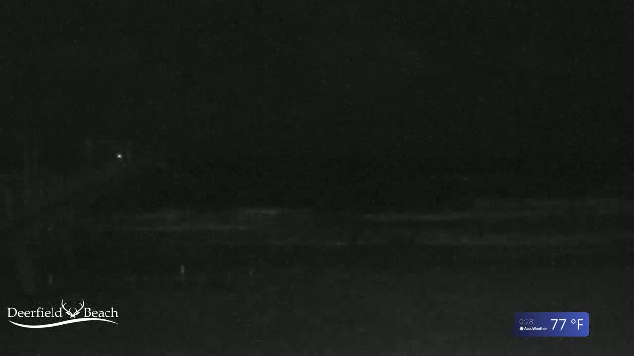 A nighttime, dark view of a beach at 77°F shows a faint, light horizon line.
