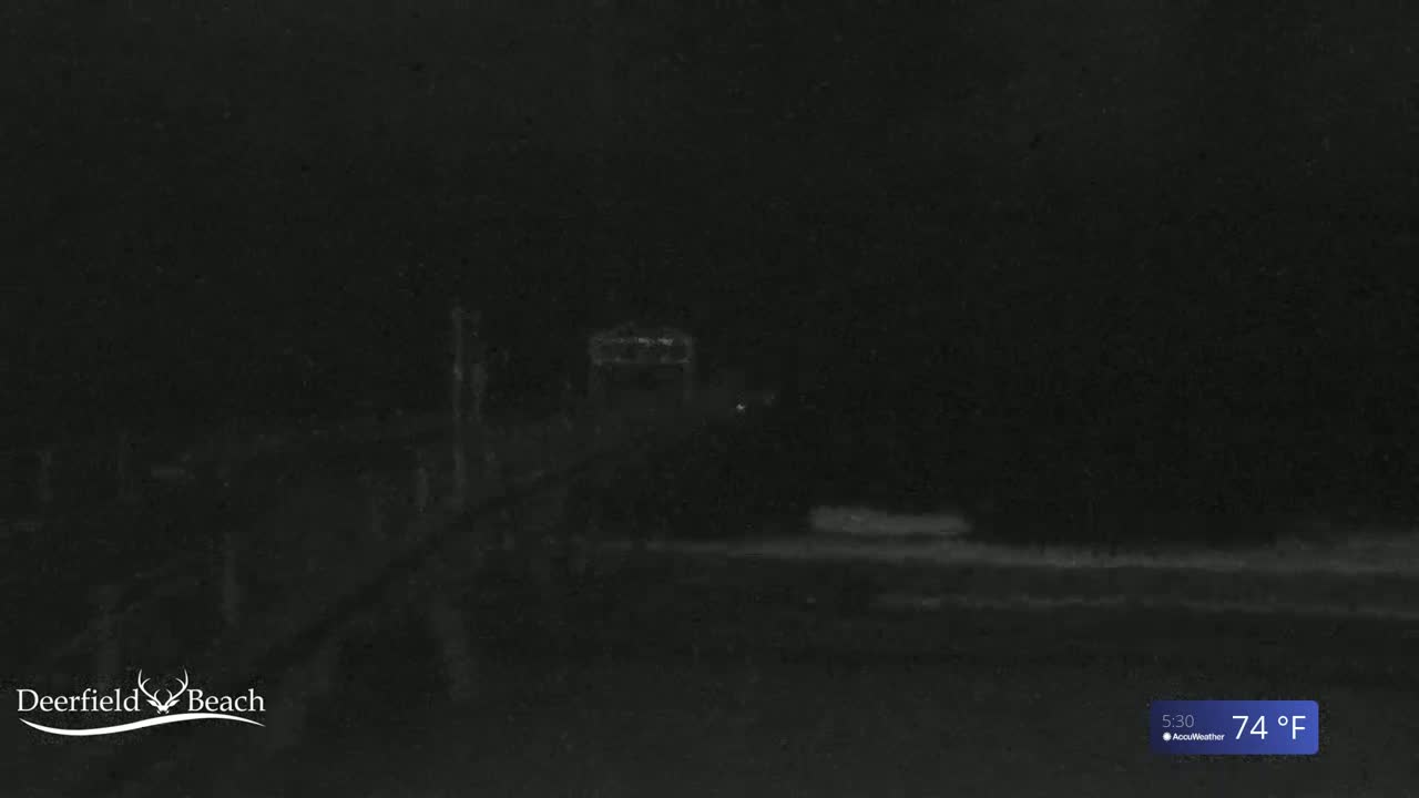 A dimly lit, nighttime scene shows a structure in the mid-ground and dark, indistinct shapes in the foreground, under a dark sky with a temperature of 74°F.