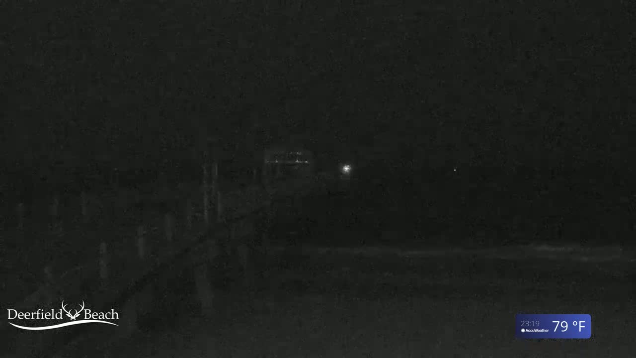 A dark nighttime scene shows a pier extending into a body of water under a clear sky, with a temperature of 79°F.