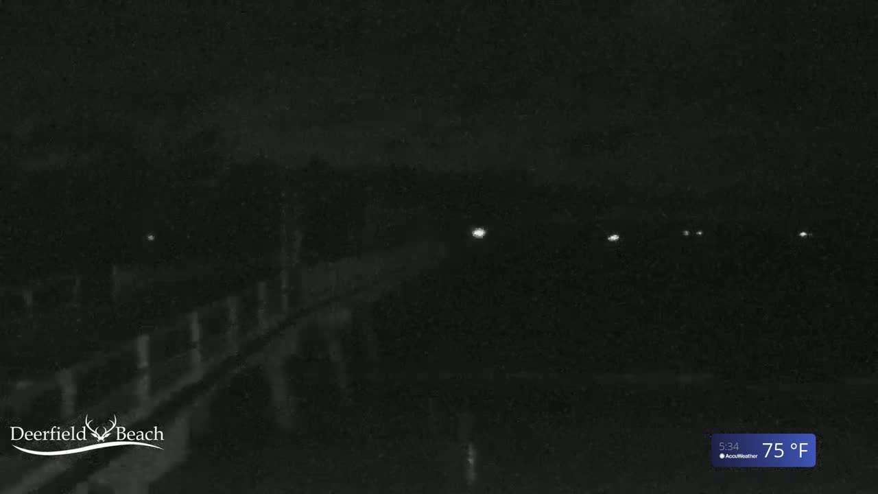 A dark, nighttime scene shows a wooden structure, possibly a pier, with a few distant lights visible under a dark sky at 75°F.