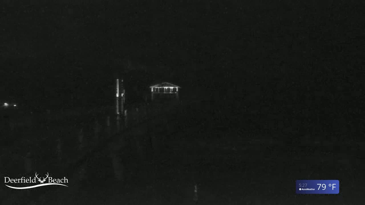 A nighttime, low-light image shows a dimly lit gazebo near the water under a dark sky, with the temperature shown as 79°F.