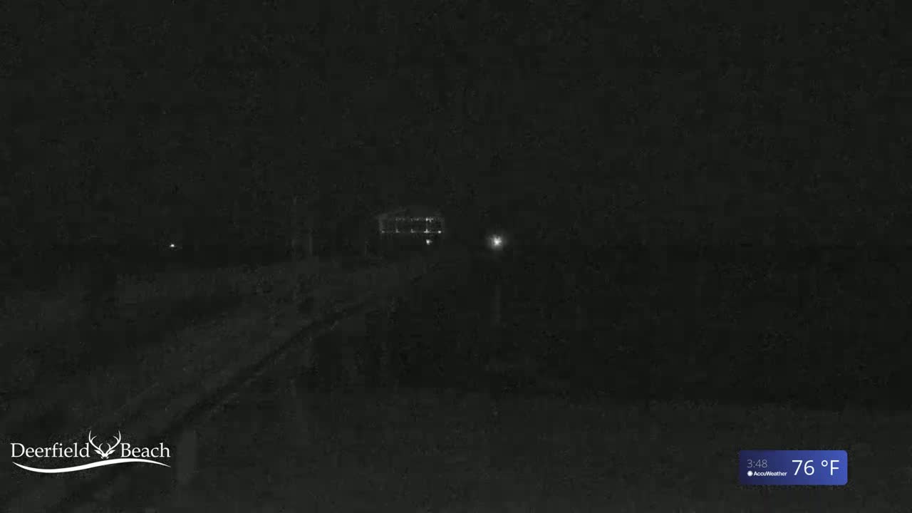 A dark, nighttime outdoor scene shows a dimly lit building and a road in the distance, under a 76°F temperature.
