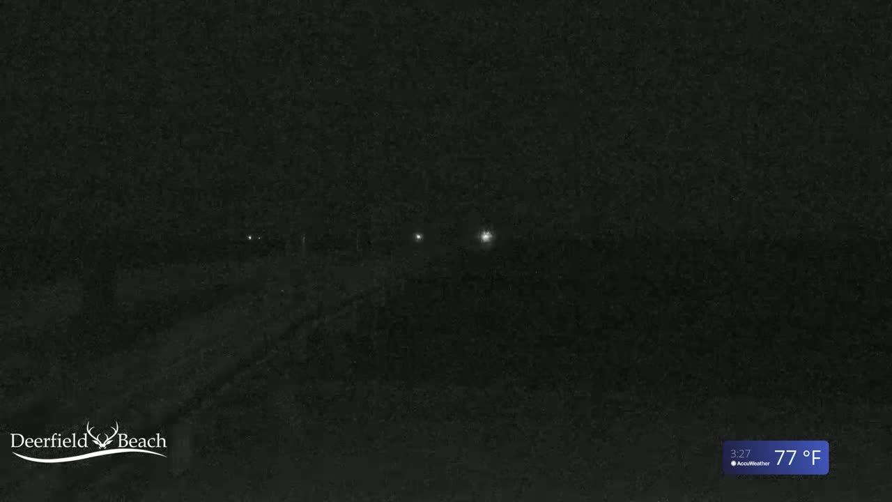A dark, nighttime scene shows a road with a few distant lights, under a 77°F sky.