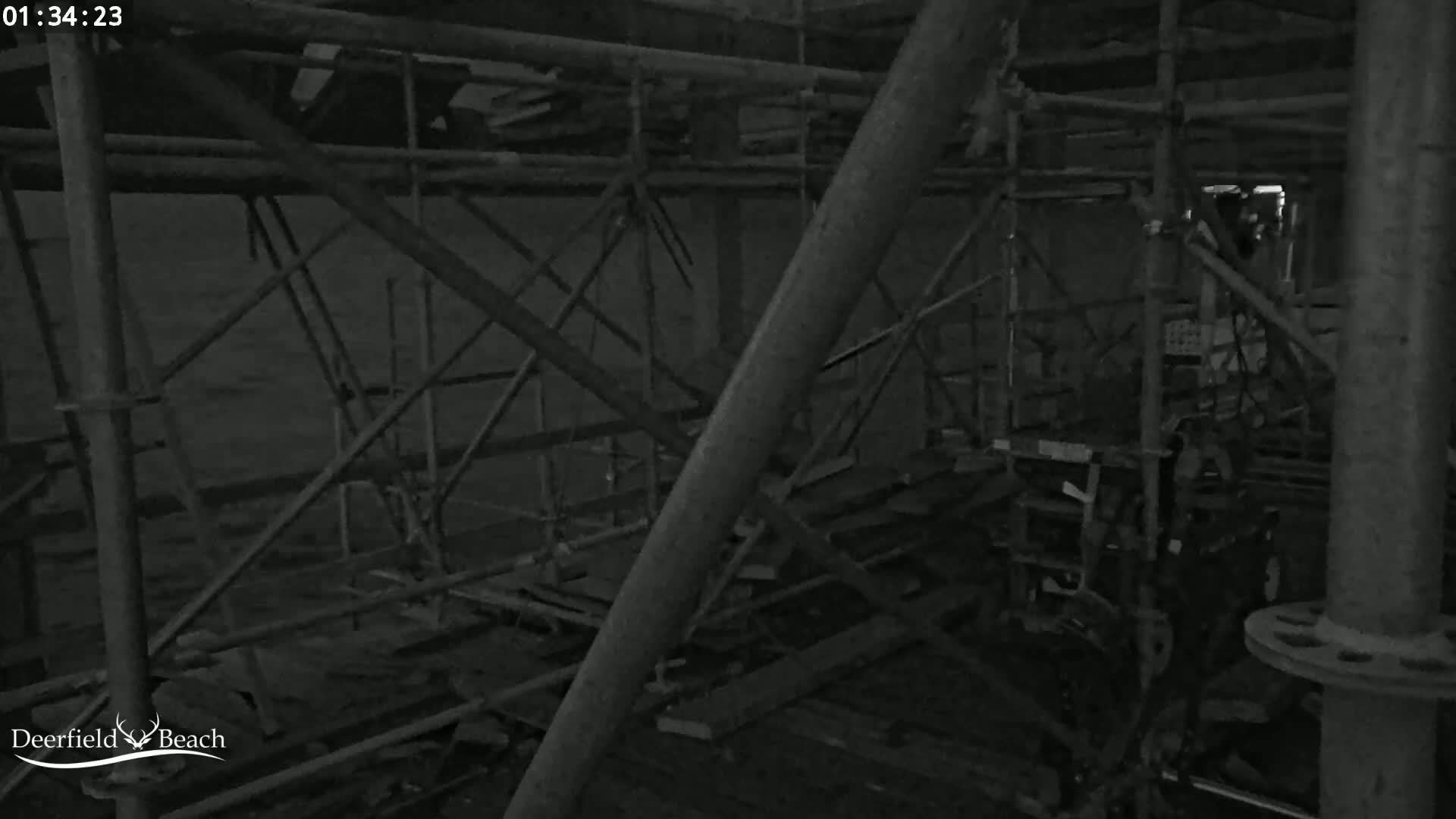 A dark, interior space shows scaffolding and various pieces of equipment at night.